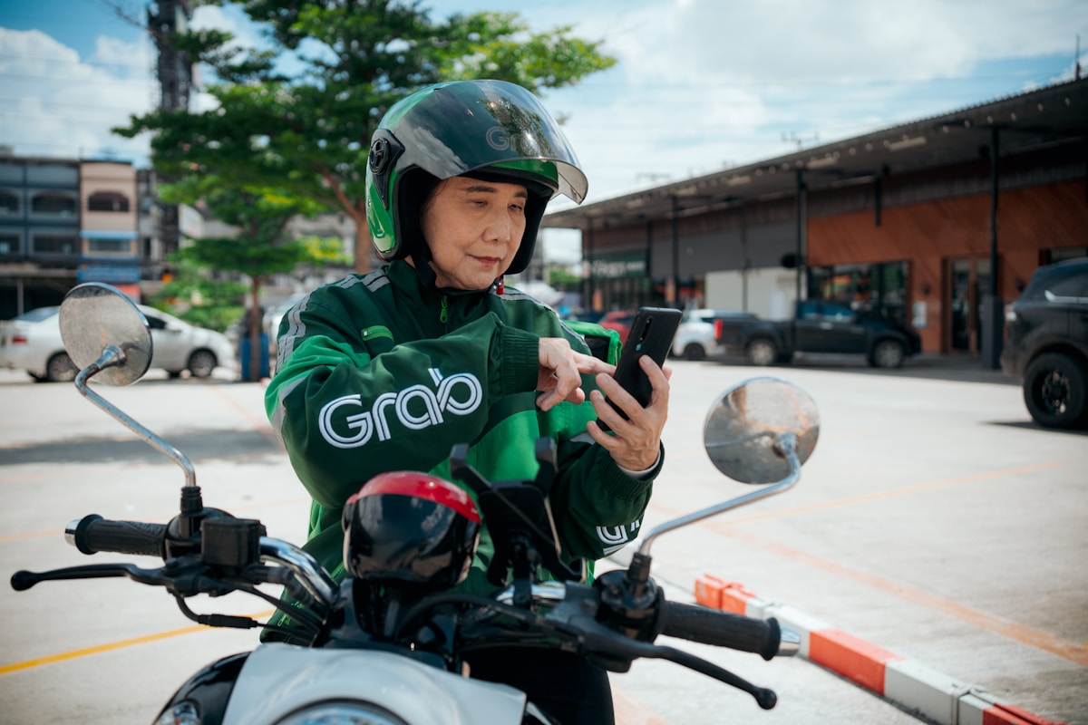 Conducteur de moto de livraison Grab utilisant un téléphone portable.