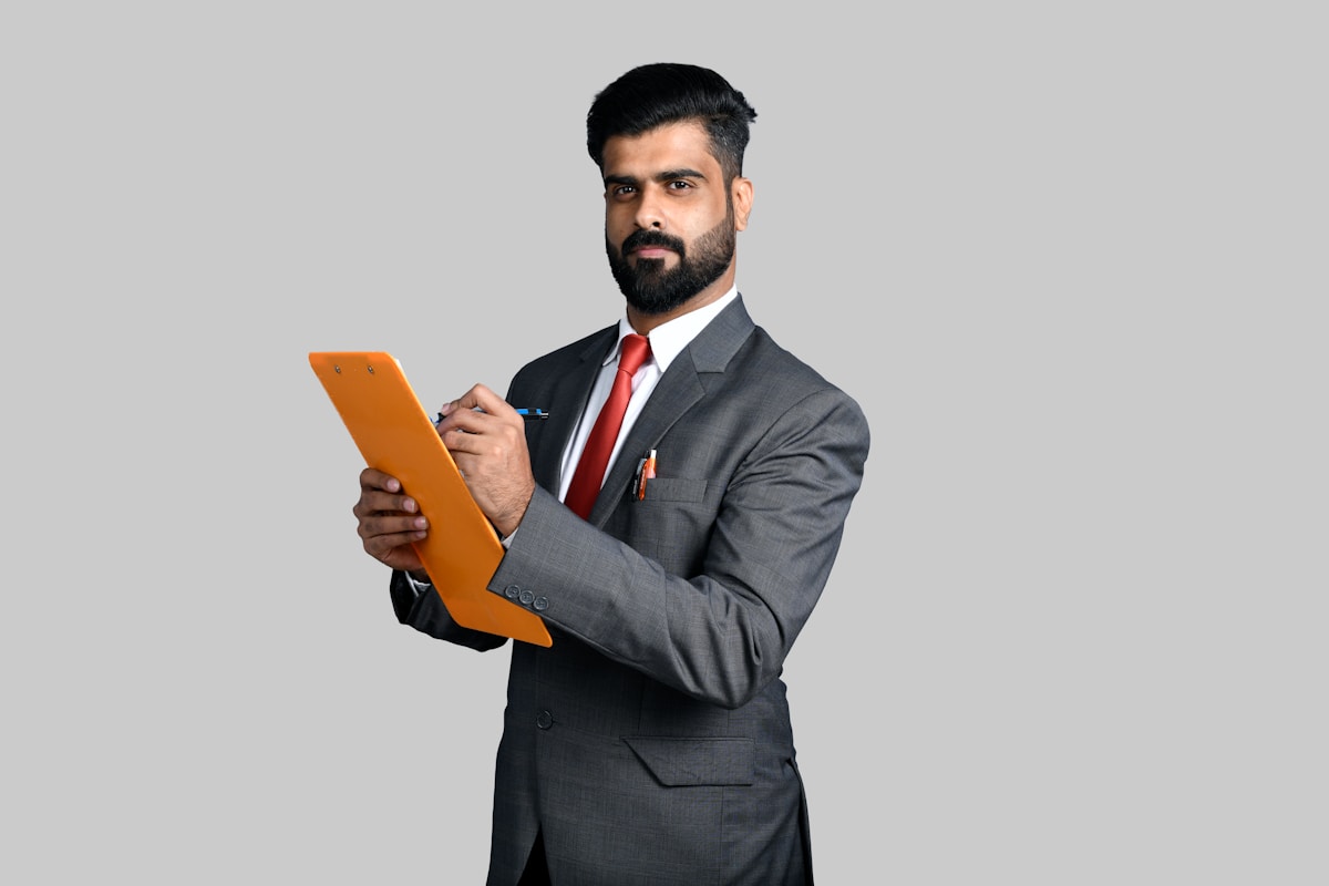 Homme d'affaires barbu en costume gris tenant une tablette orange.