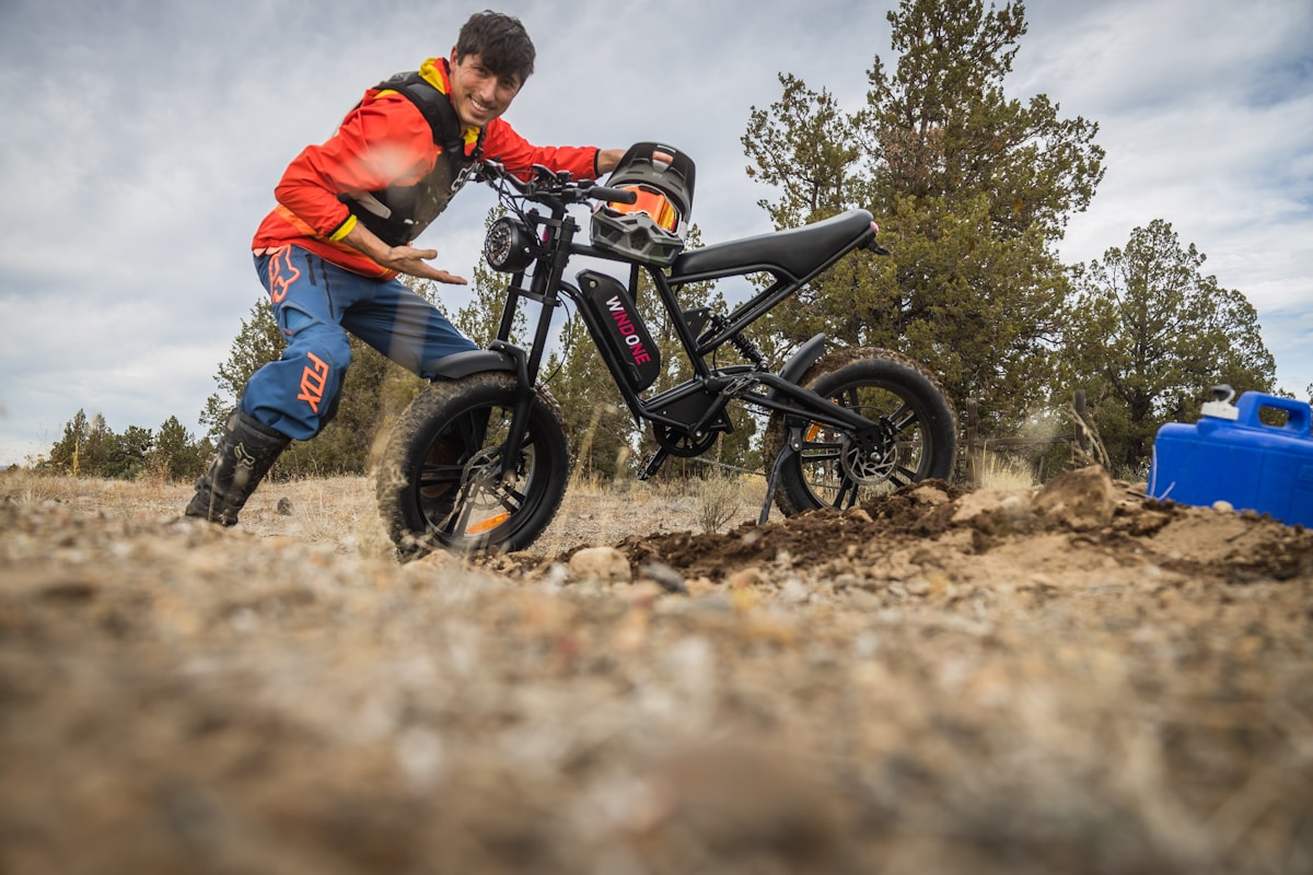 Homme en tenue de motocross sur une moto électrique tout-terrain.