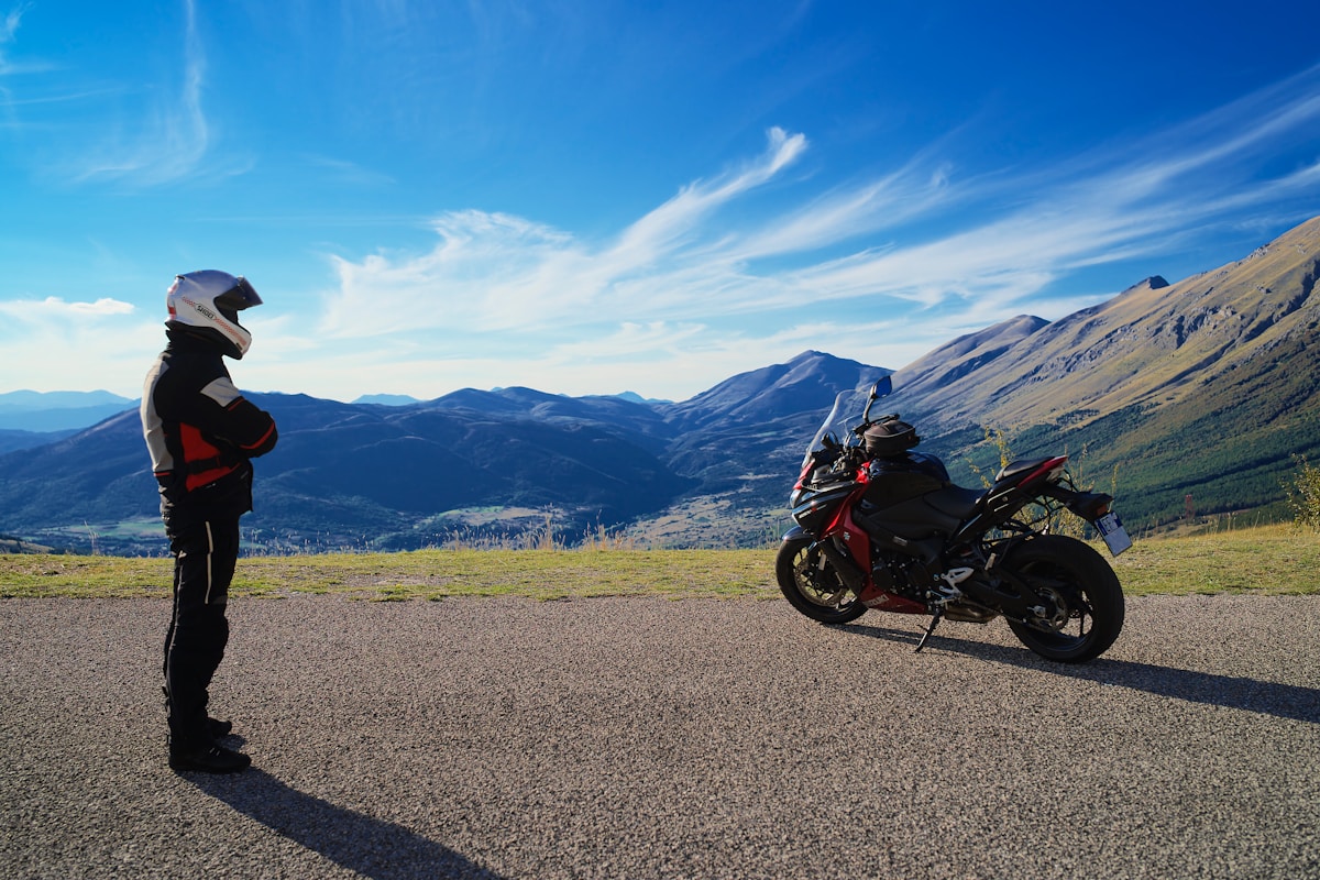 Motard sur une moto de sport contemplant un paysage montagneux.