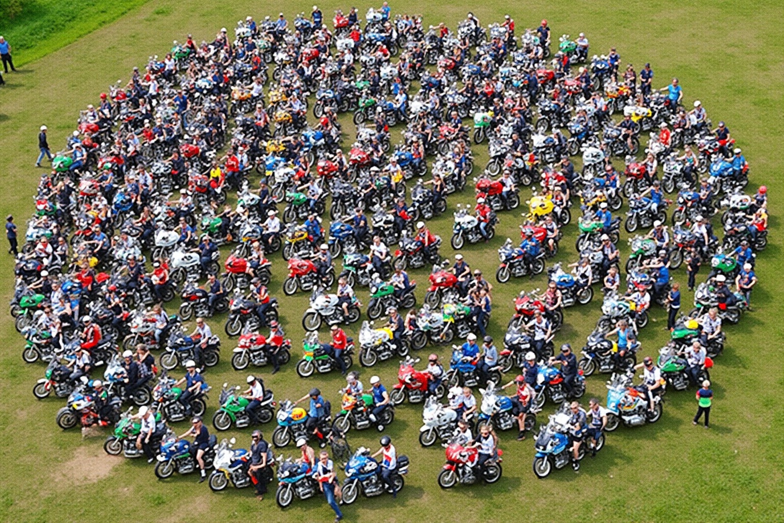 Rassemblement massif de motards sur un terrain verdoyant.