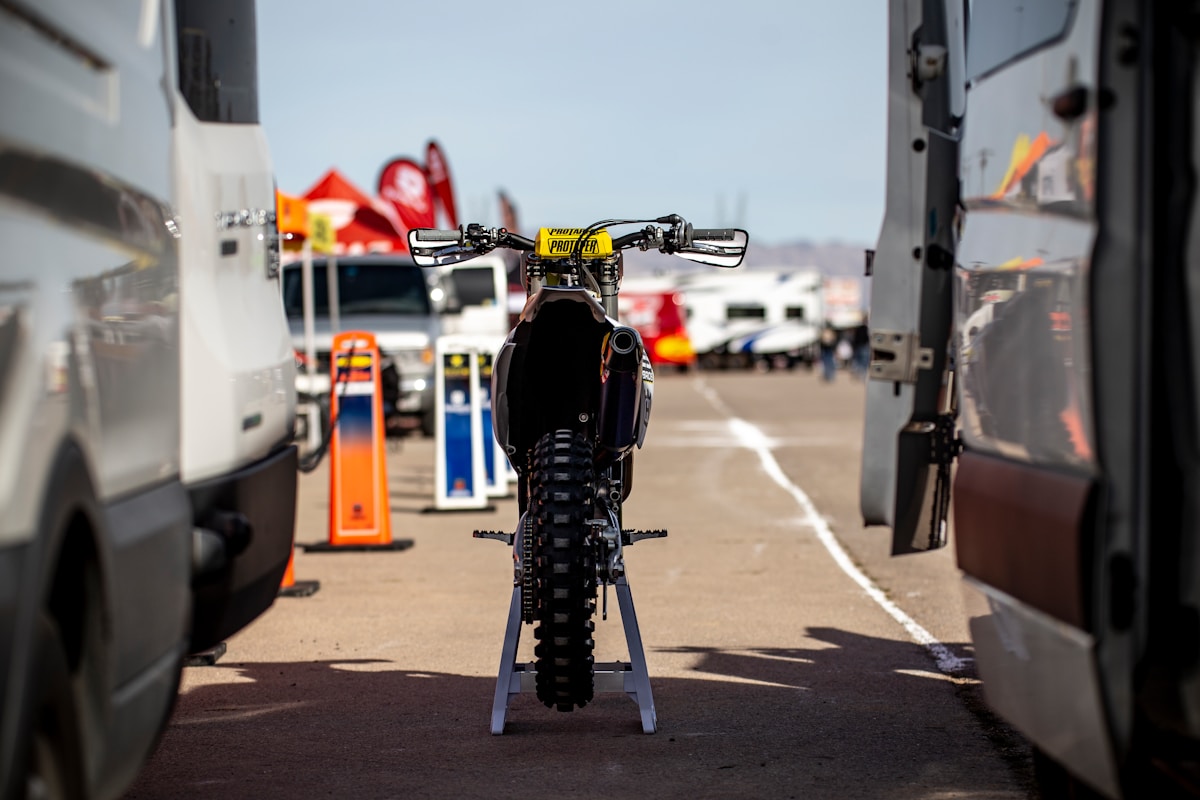 Moto tout-terrain noire avec équipement de course dans un paddock.