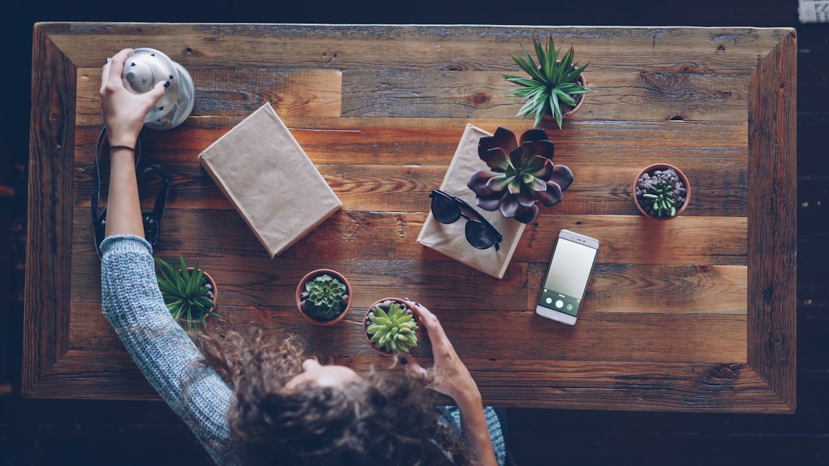 Une femme disposant des plantes sur une table en bois.