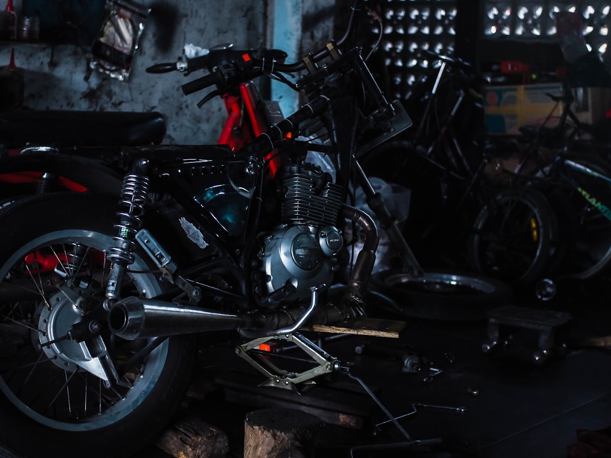 Moto noire et rouge dans un atelier sombre et encombré.