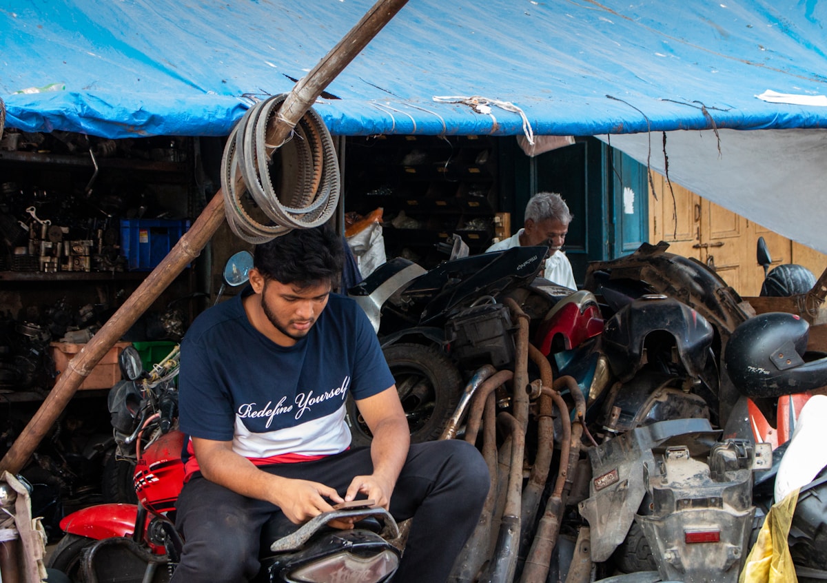 Atelier de réparation de motos avec homme travaillant sur un scooter.