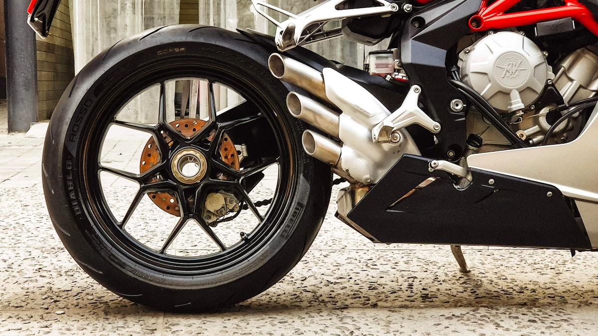Roue de moto sport avec jante noire et étriers de frein orange.