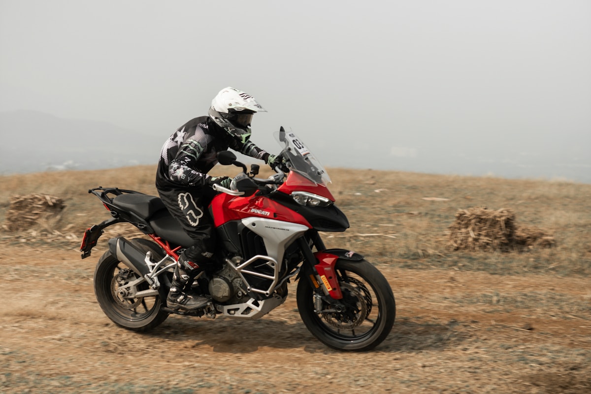 Motocycliste sur une moto Ducati traversant un paysage désertique.