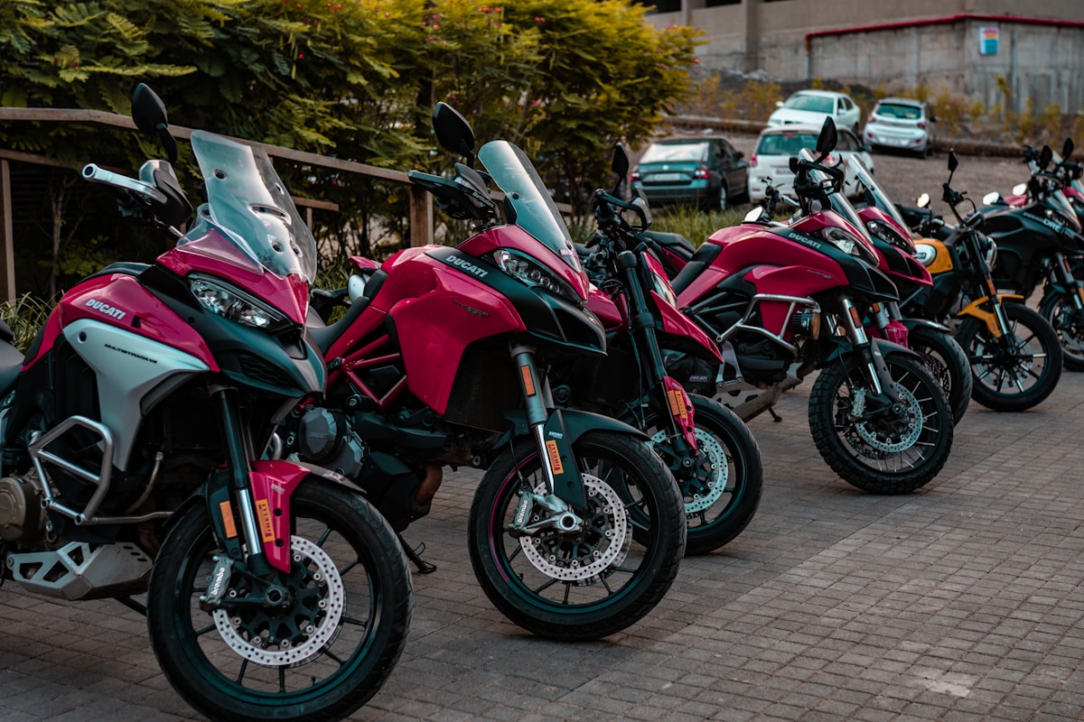 Rangée de motos Ducati rouges et turquoises garées dans la rue.