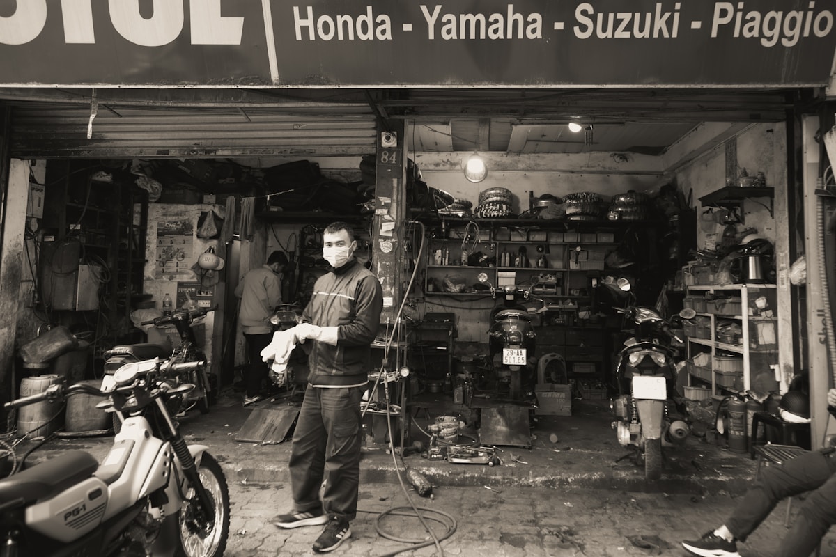 Atelier de réparation de motos avec mécanicien en tenue de travail.