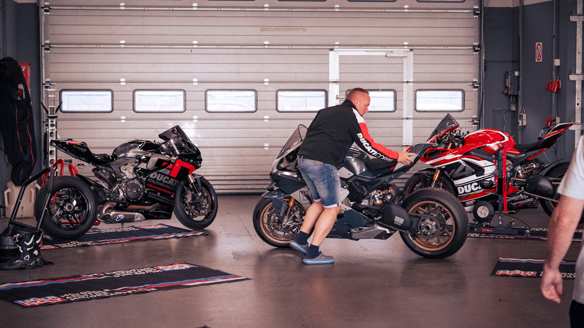 Un homme pousse une moto dans un garage.