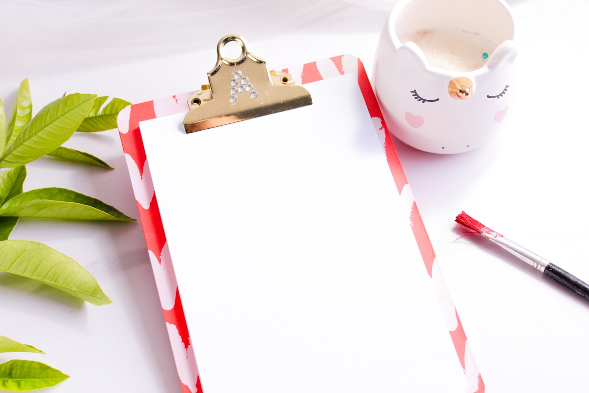 Presse-papiers décoratif avec feuilles vertes, tasse de café et pinceau.