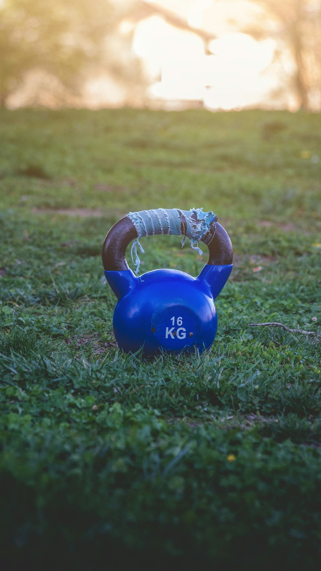 Gros plan sur les mains d'une personne saisissant un kettlebell pendant un entraînement, avec un arrière-plan de salle de sport flou.
