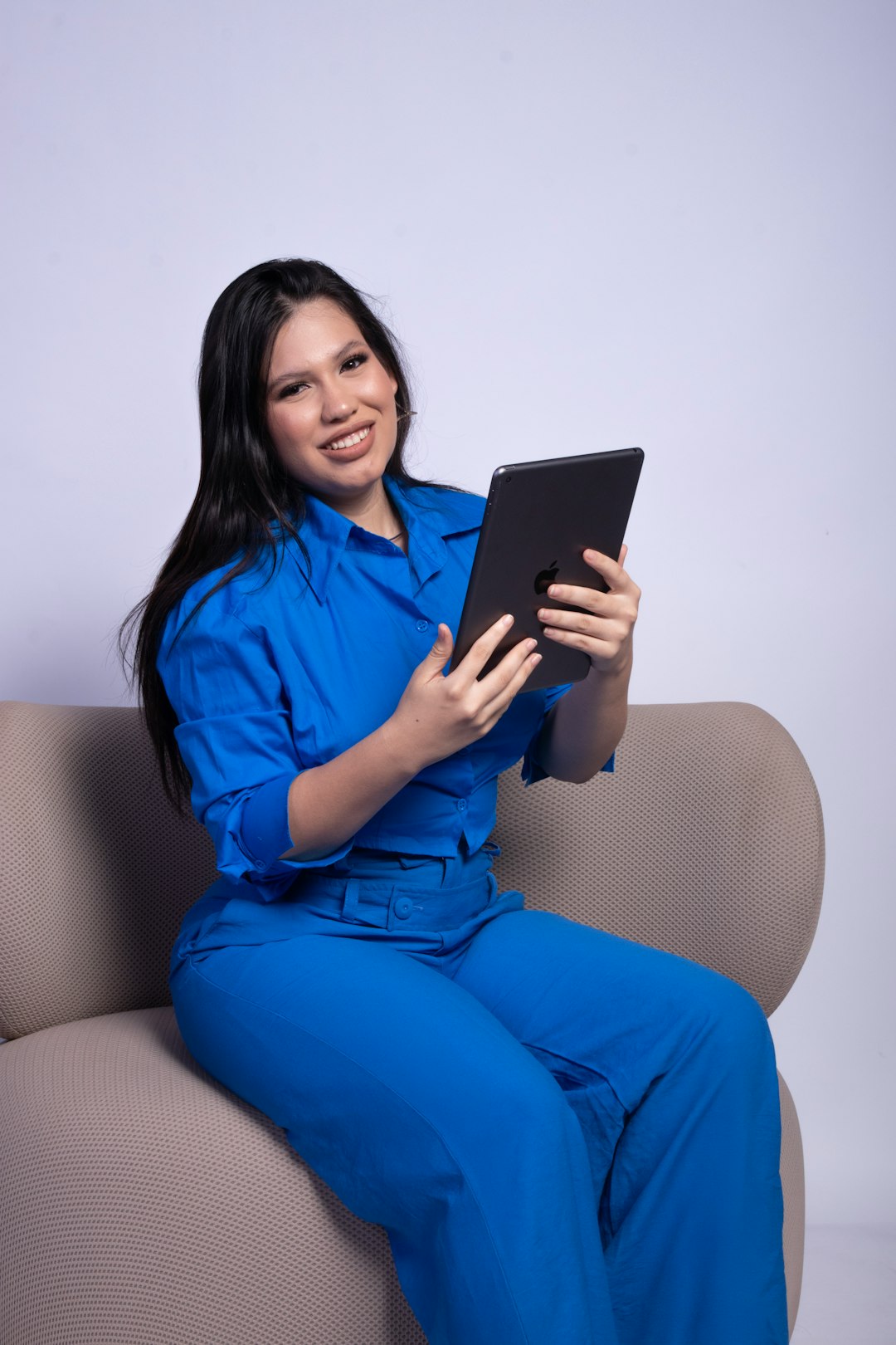 A professional woman in a business suit looking confidently at a growing chart on a tablet, symbolizing business growth through technology.