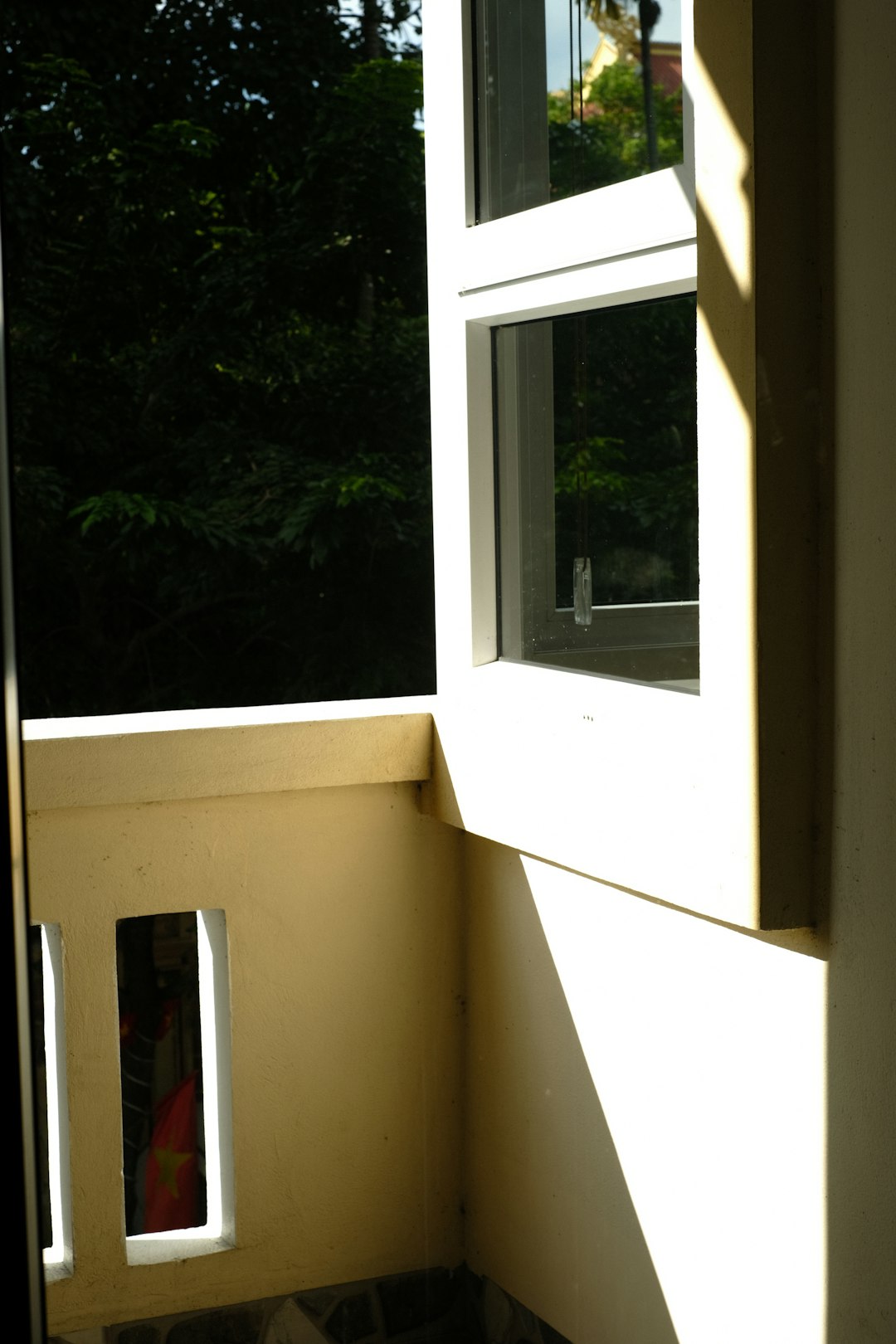Une façade de maison moderne avec des stores extérieurs abaissés, protégeant les fenêtres du soleil intense de l'après-midi.