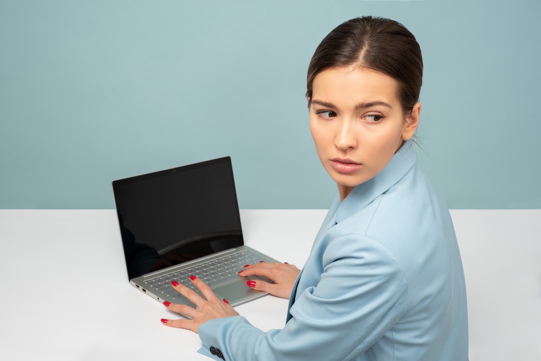A business professional sits at a clean desk, using a laptop. The screen displays a vibrant website editor with easy-to-use drag-and-drop components.