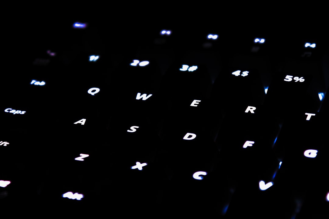 Close-up of hands typing on a laptop keyboard with blurred city lights in the background, symbolizing tech work. Photo by Philipp Katzenberger on Unsplash.
