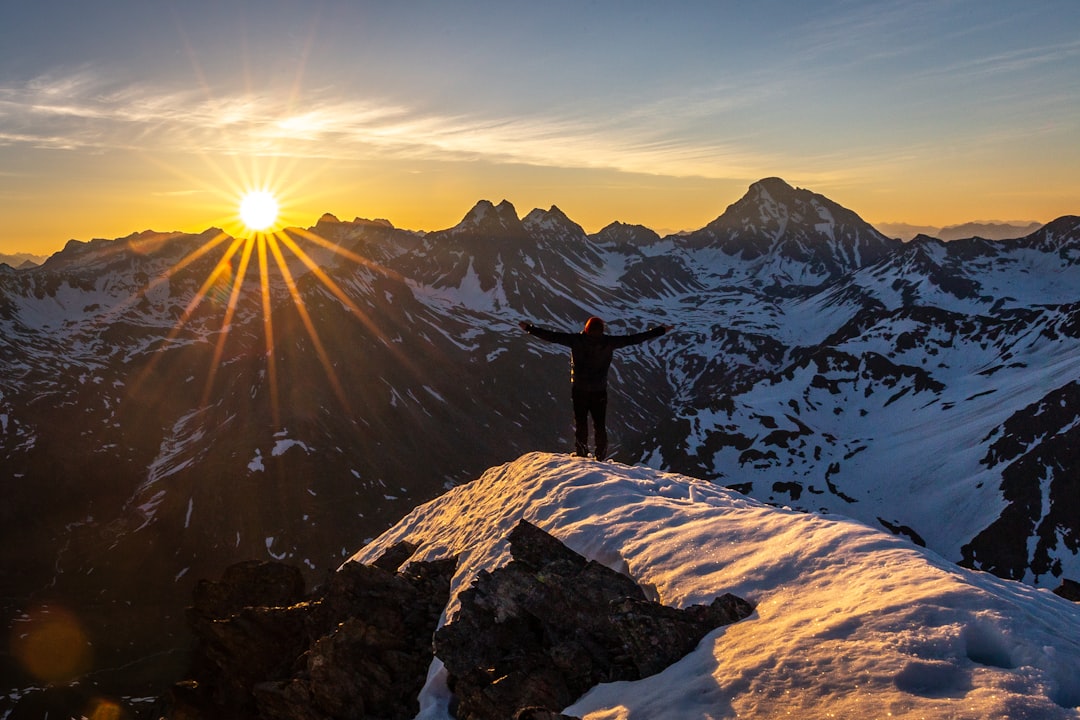 Un alpiniste qui arrive au sommet d'une montagne suisse au lever du soleil. L'image classique du succès en affaires.