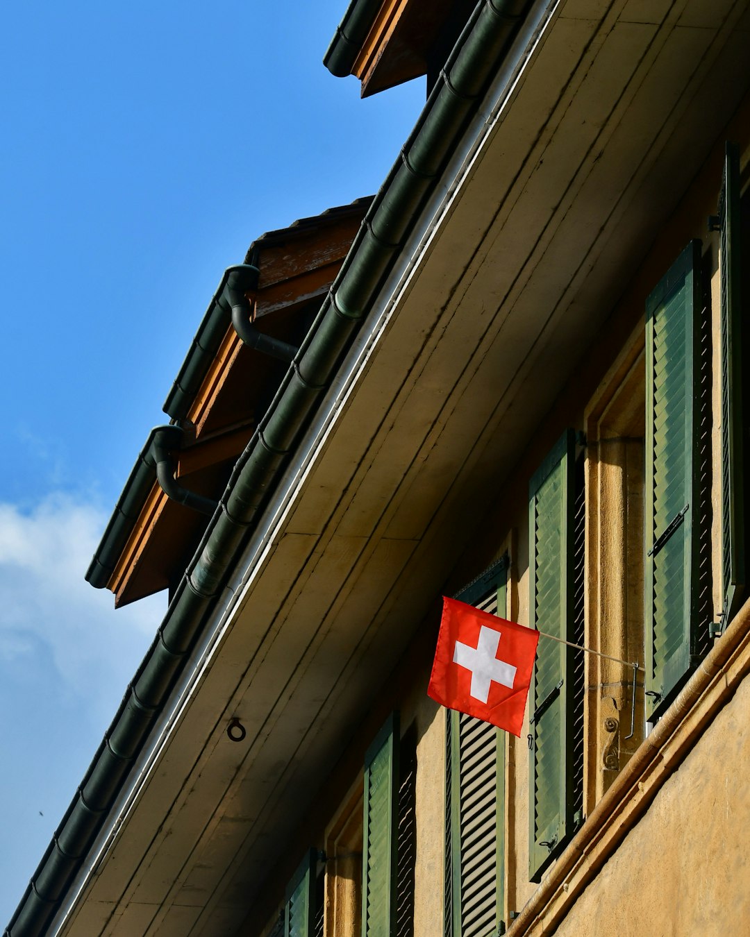 A close-up of a Swiss flag with a clean, modern office building in the background.