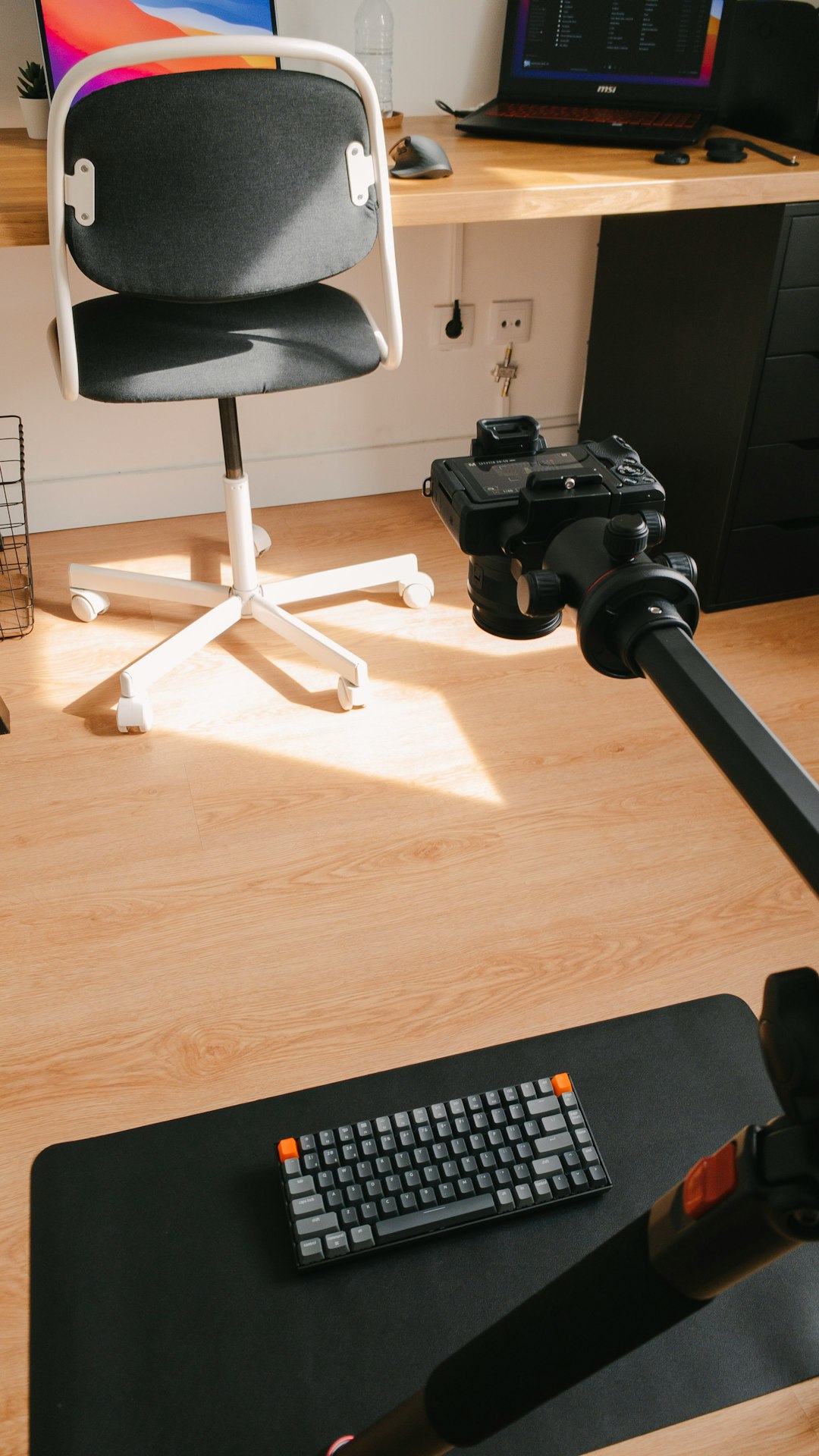 A person works at a clean, modern desk with sunlight coming through the window.