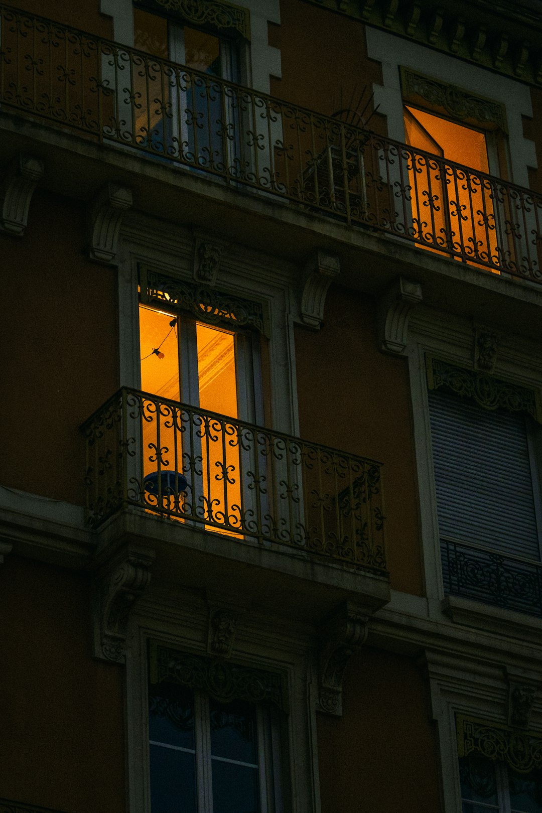 Une personne se relaxe avec un livre sur un balcon ensoleillé, où un store extérieur crée une zone d'ombre agréable et une atmosphère sereine.