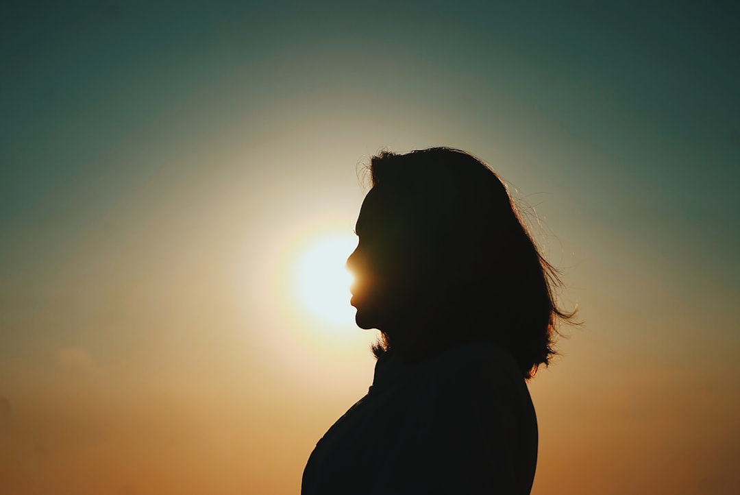 Une femme enceinte sourit en posant ses mains sur son ventre, dans un environnement naturel et paisible. Image symbolisant les soins périnataux en ostéopathie.