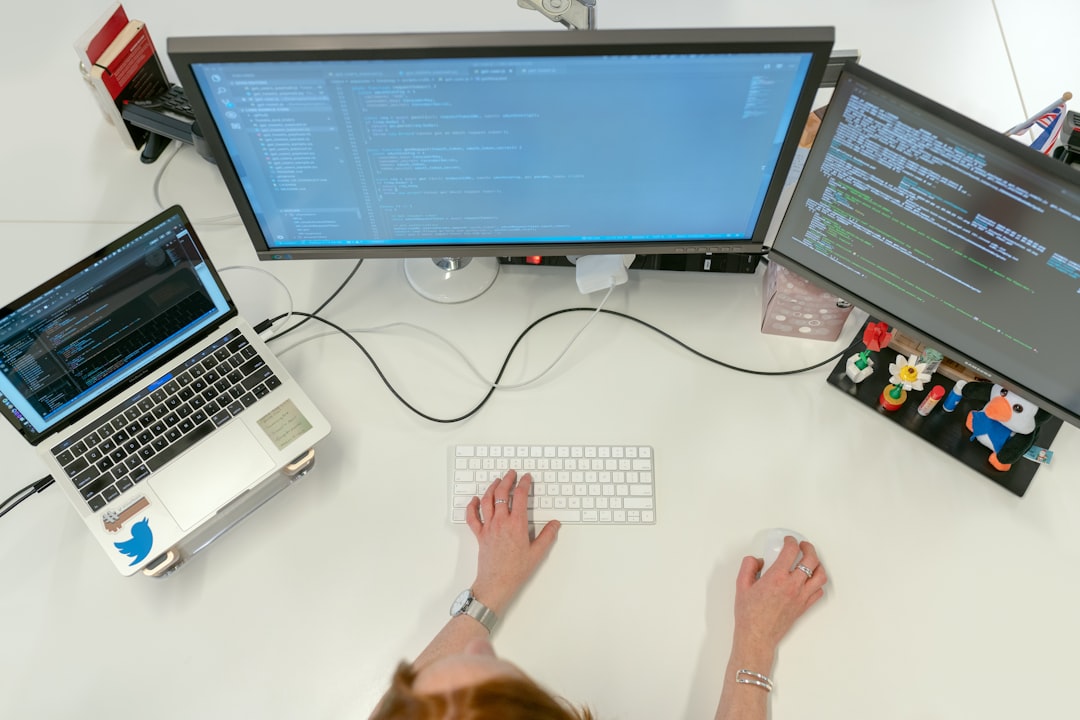 A developer's hands typing on a laptop with lines of code on the screen, in a modern and clean office environment.