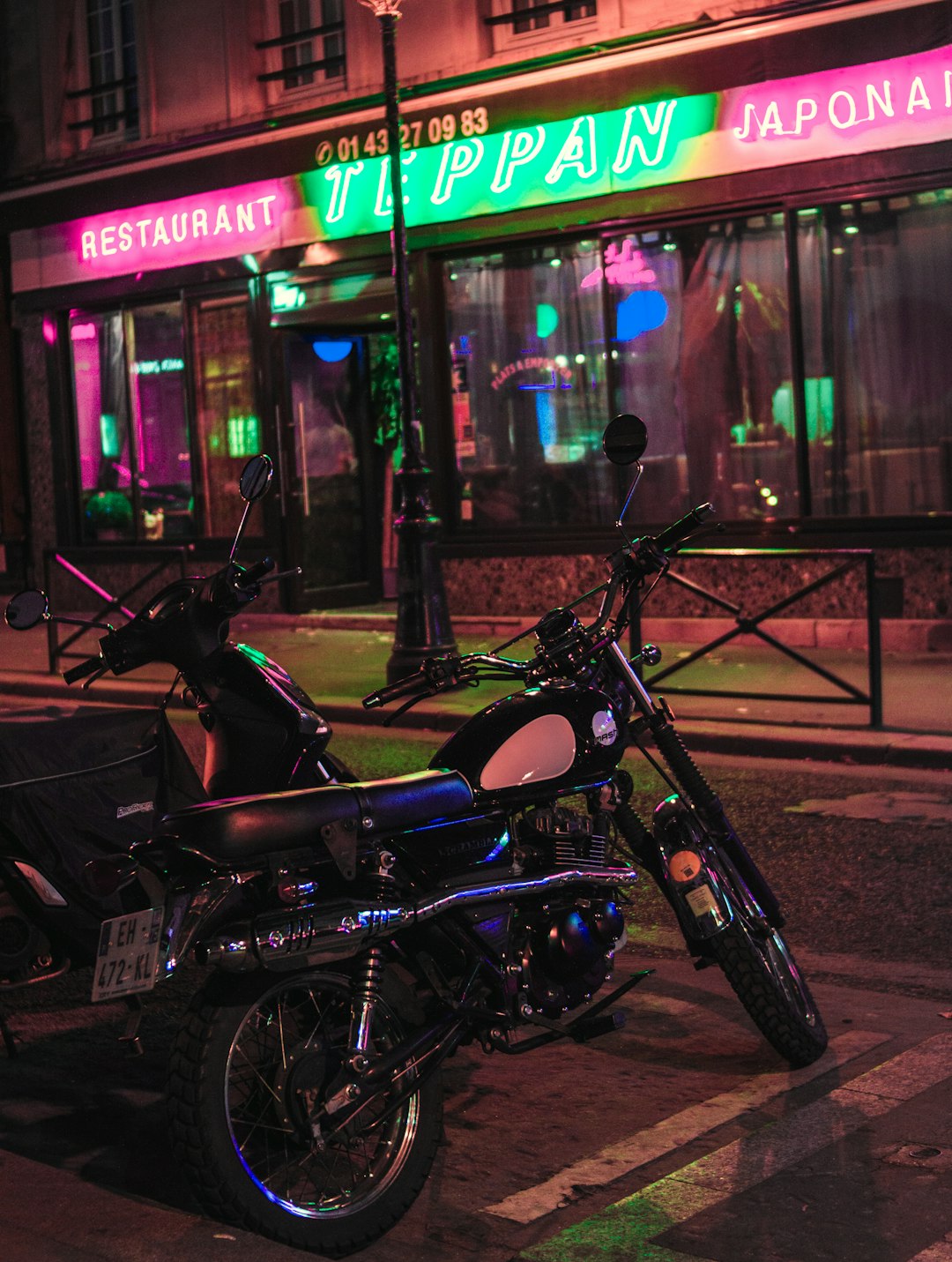 Vue extérieure d'un pub de style américain la nuit, avec des néons lumineux et des motos garées devant.