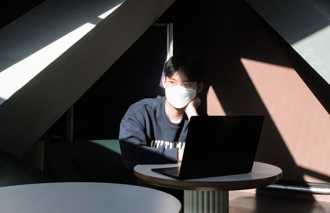 A focused person working on a laptop at a bright, modern co-working space with plants in the background. Photo by Austin Distel on Unsplash.