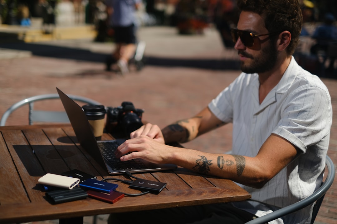 Close-up of hands typing on a laptop, with the soft-focus background of a lively cafe or co-working spot.