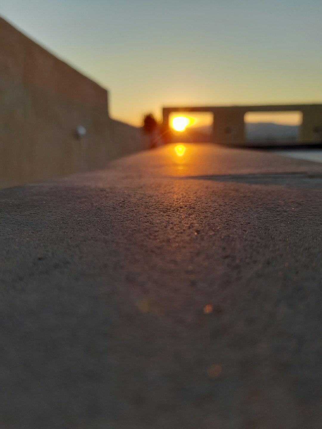 Une terrasse ensoleillée avec un grand store banne au tissu coloré, protégeant une table et des chaises.