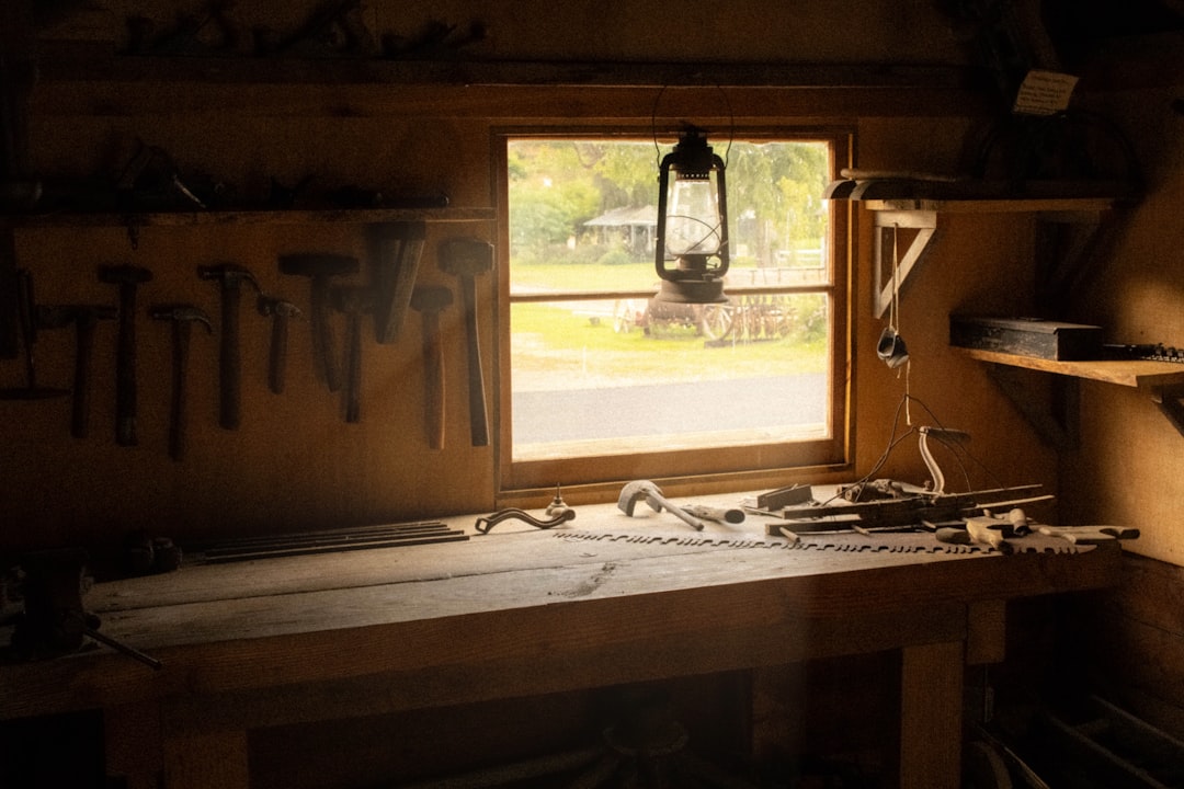 Un artisan travaillant le bois dans son atelier, se concentrant sur un détail avec des outils à la main. L'ambiance est authentique et met en valeur le savoir-faire.