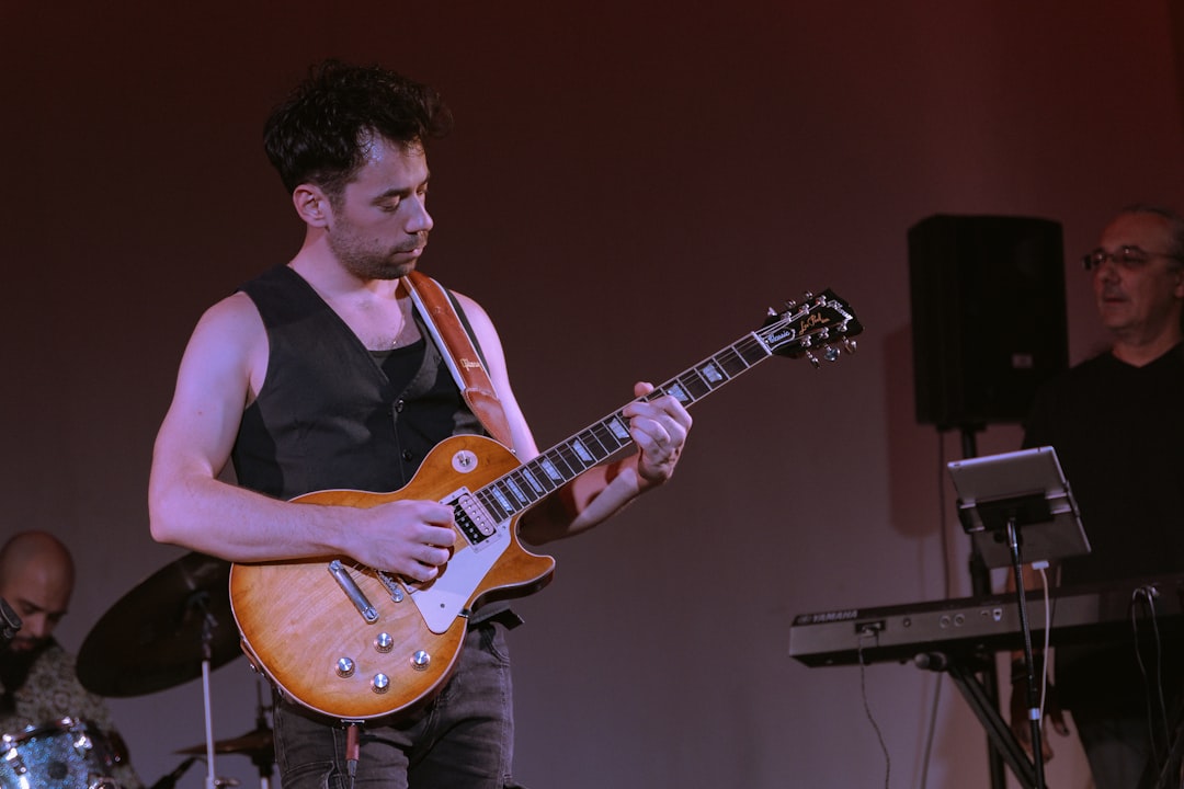 A musician playing an electric guitar on a dimly lit stage during a live concert in a small venue.