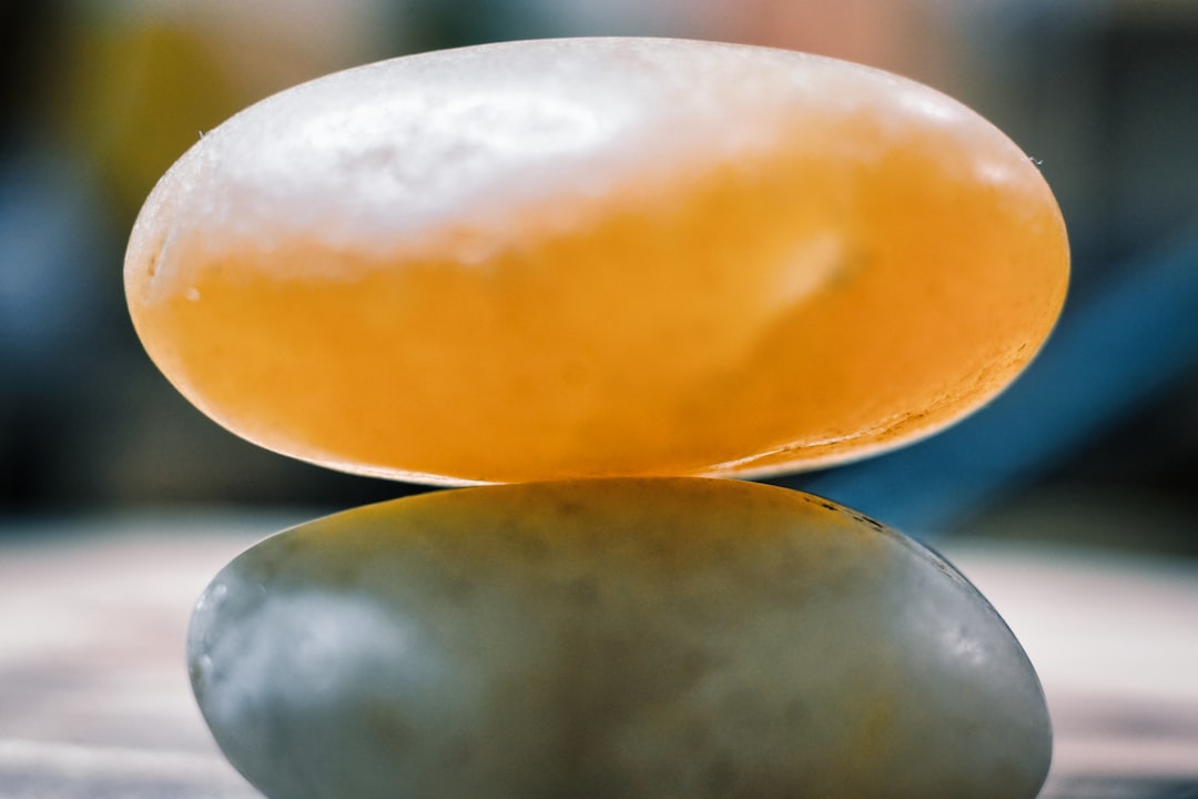 Des pierres de chakra colorées alignées sur un fond de bois, symbolisant l'équilibre et l'harmonie énergétique. Photo par Conscious Design sur Unsplash.