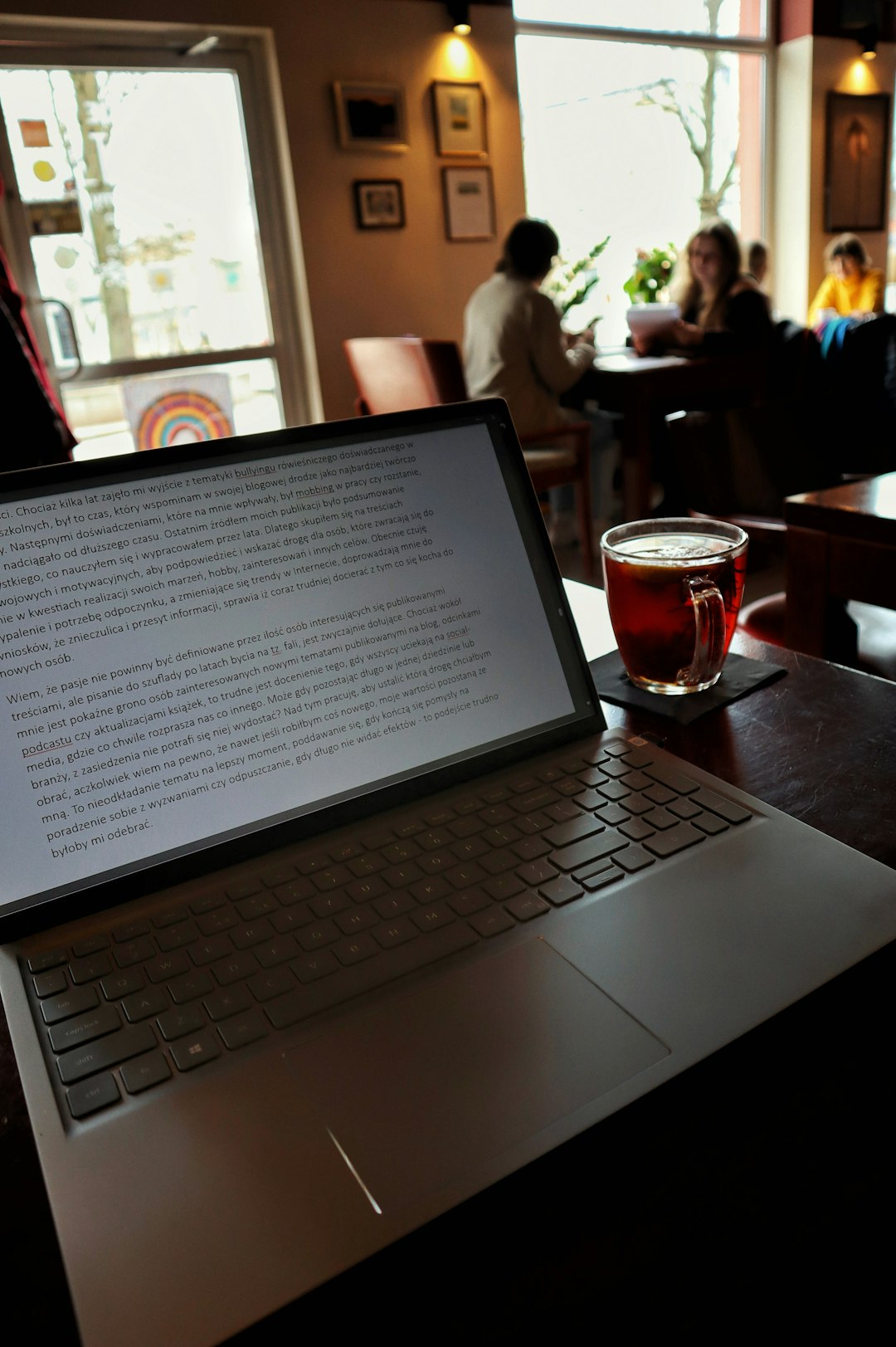 a writer focused on his laptop in a relaxed, well-lit cafe, embodying the creative process of content creation.