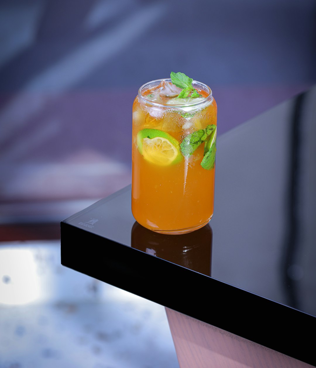 Un cocktail ou mocktail coloré dans un verre élégant, garni d'une tranche de citron et de menthe, servi dans un bar. Photographe: Stanislav Ivanov sur Unsplash.