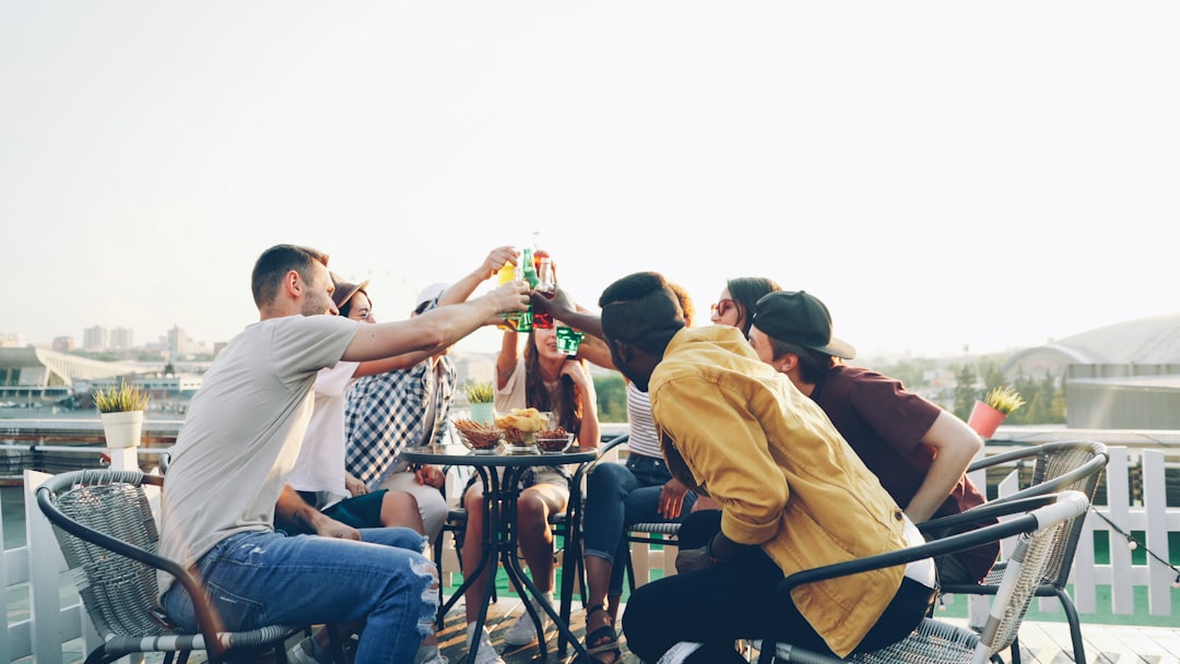 Un groupe de jeunes adultes diversifié trinquant avec des bouteilles de Grano Maté dans un bar branché et lumineux. Photographe: Helena Lopes sur Unsplash.
