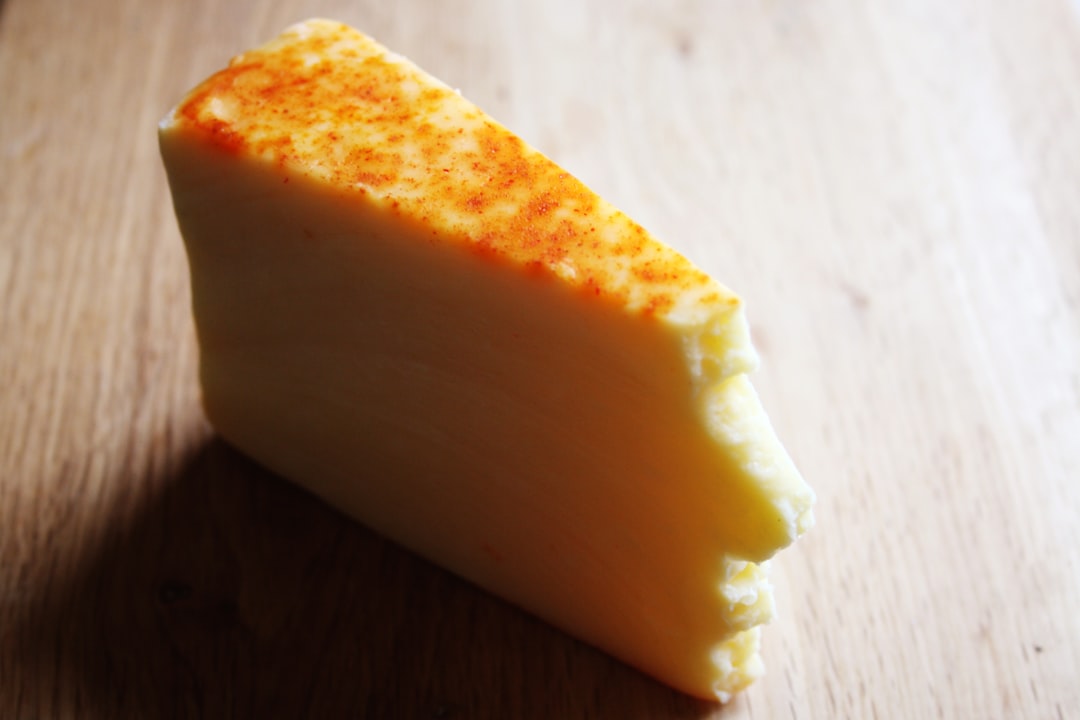 Fromage Gruyère râpé tombant en cascade d'une râpe en métal sur une planche à découper en bois.