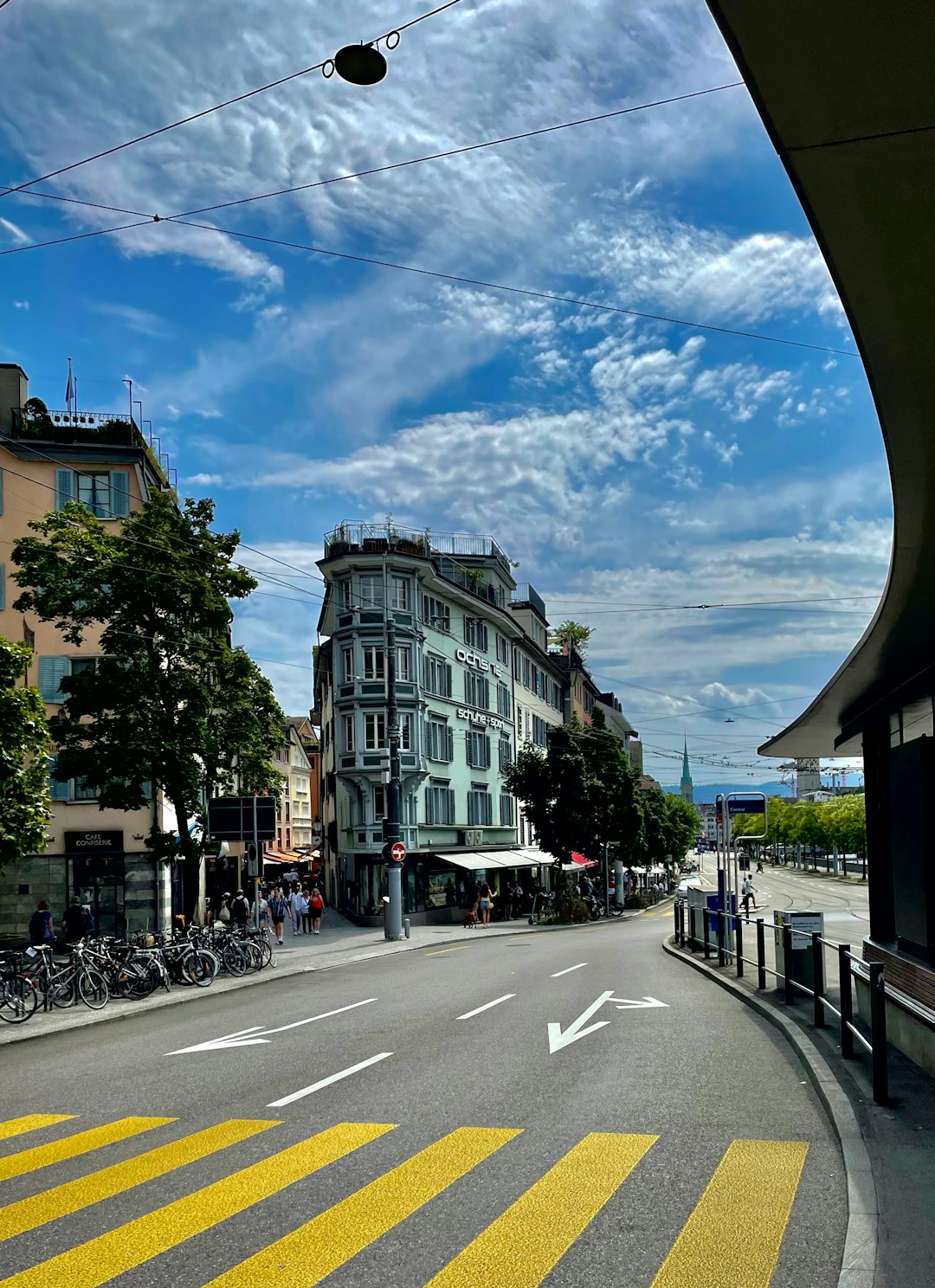 Une rue commerçante pittoresque dans une ville suisse comme Lausanne ou Genève, avec des bâtiments historiques et des enseignes locales. Le temps est ensoleillé.