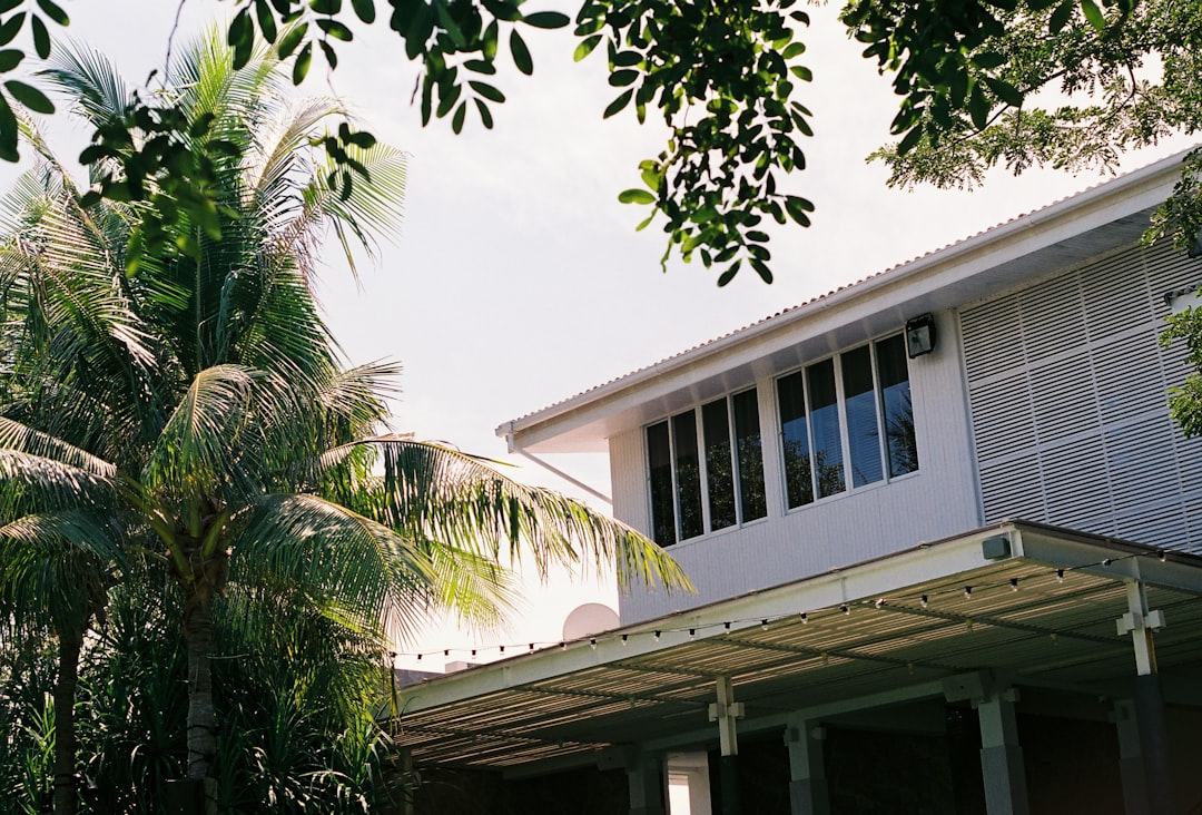 Une main tenant un stylo pointant vers un devis de rénovation, avec une calculatrice à côté sur un plan de maison.