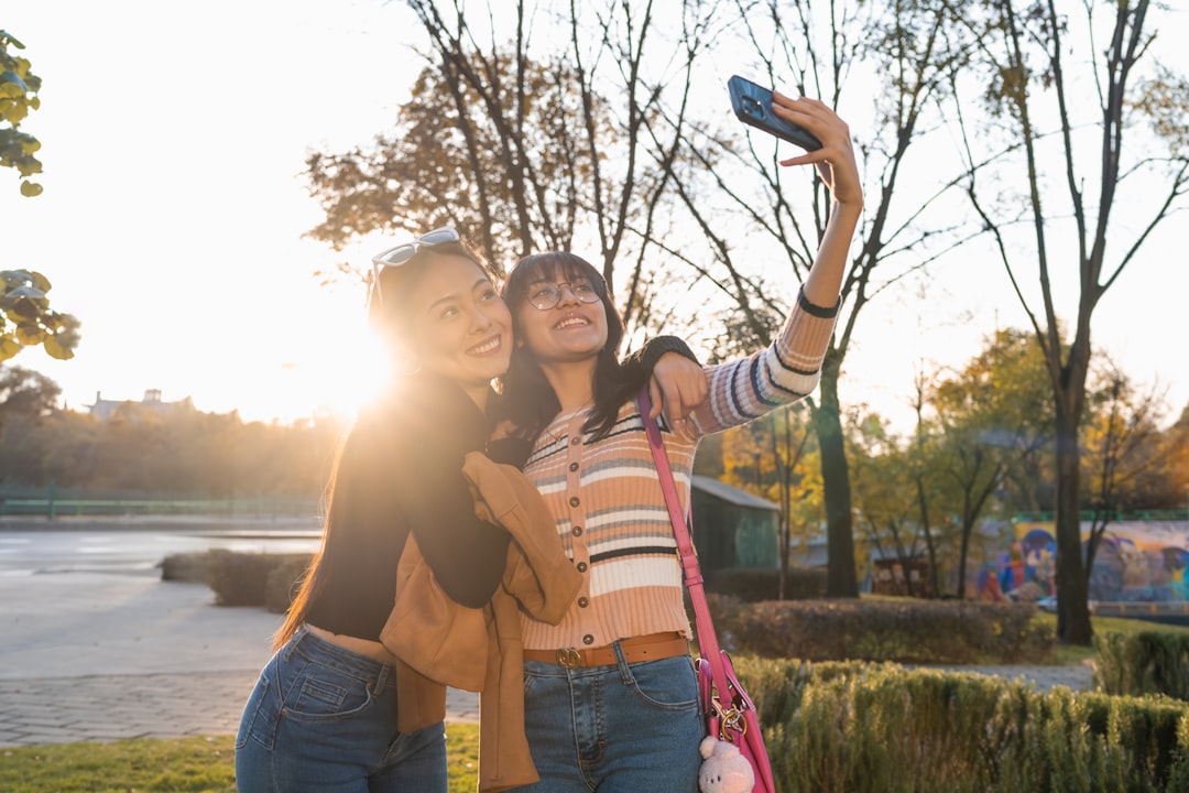 Un groupe d'amis souriants regardant ensemble des photos sur un smartphone, partageant un moment de convivialité.