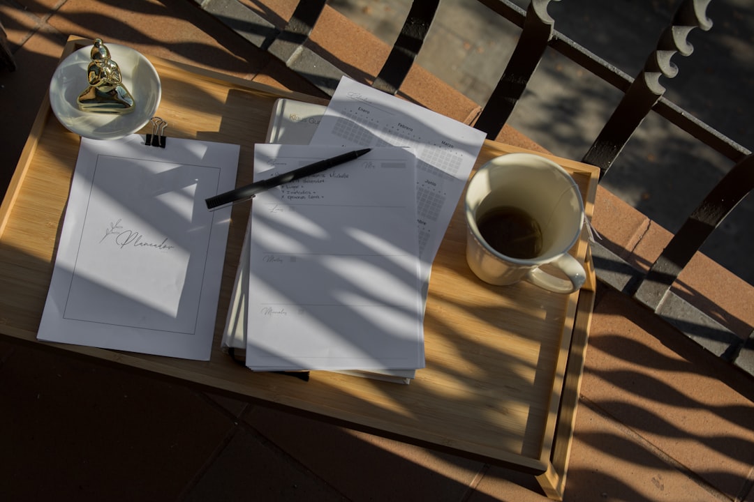 Un bureau de travail élégant avec un carnet ouvert, un stylo et une tasse de café, suggérant la planification et la stratégie. Photo par Taisiia Stupak sur Unsplash.