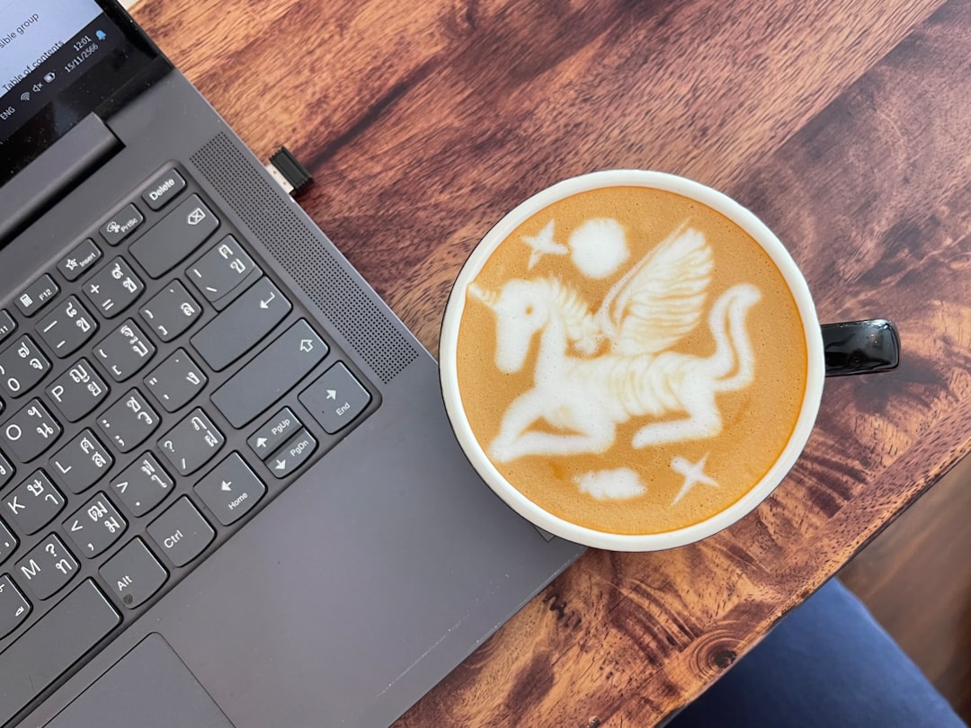 An artist sits at a sunlit cafe table with a latte. They are looking thoughtfully at a laptop screen which displays a clean dashboard with earnings data and charts.