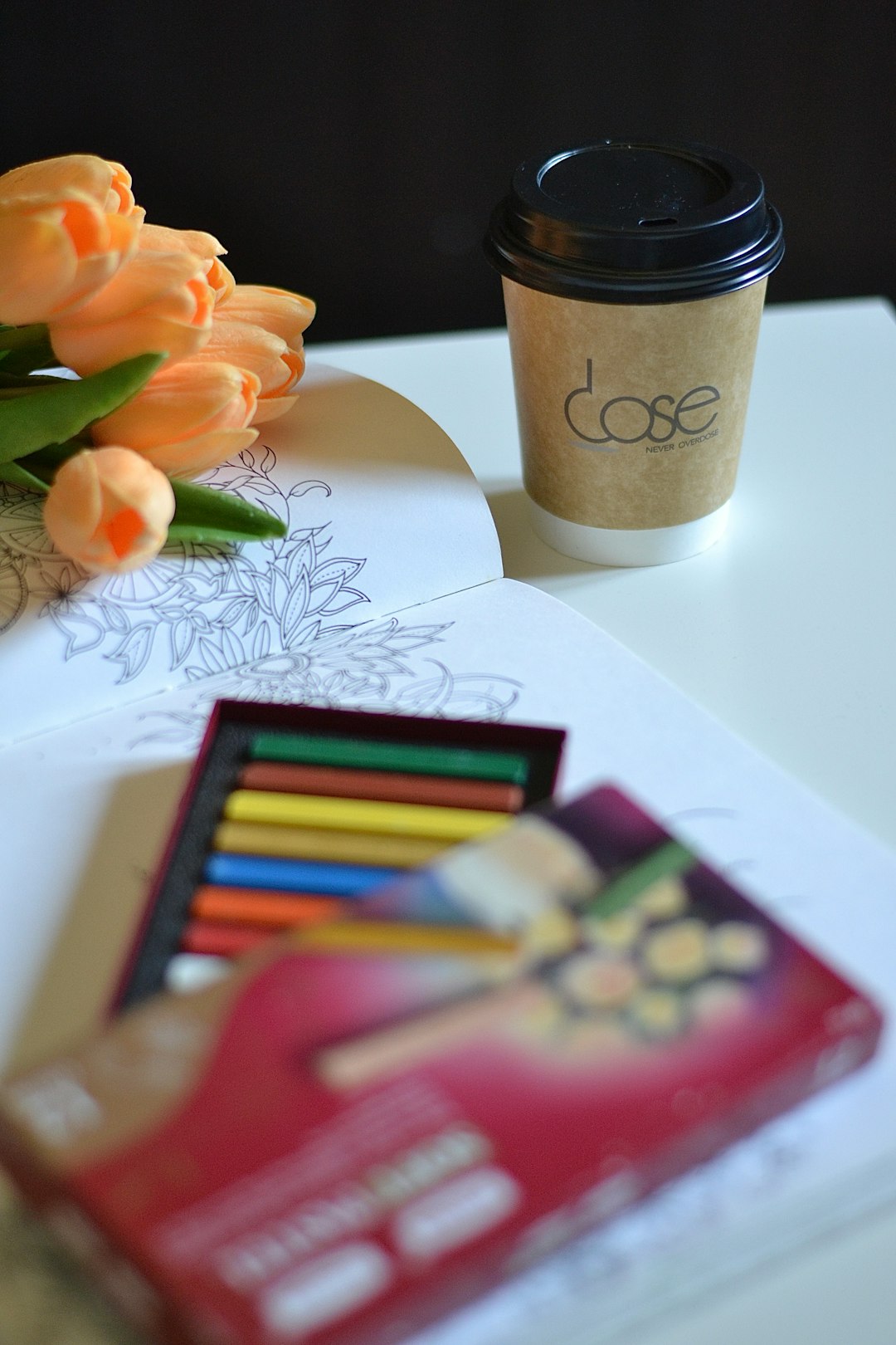 An overhead view of a creative workspace. On the desk are a sketchbook with drawings, a set of watercolor paints, a steaming mug of coffee, and a smartphone displaying a QR code.