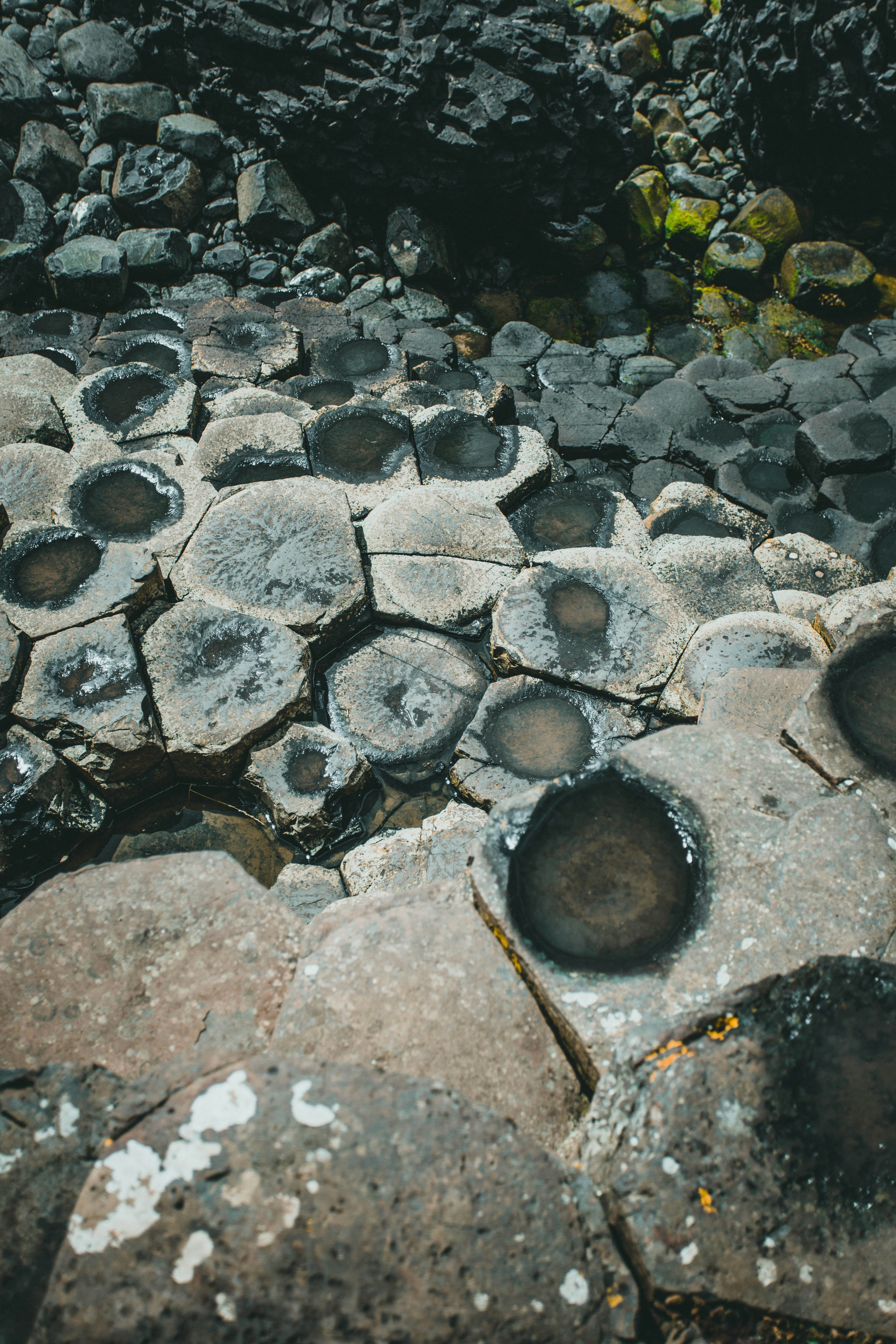 Une pile de pierres de basalte noires lisses utilisées pour le massage aux pierres chaudes, posée sur une serviette blanche, avec une fleur d'orchidée à côté.