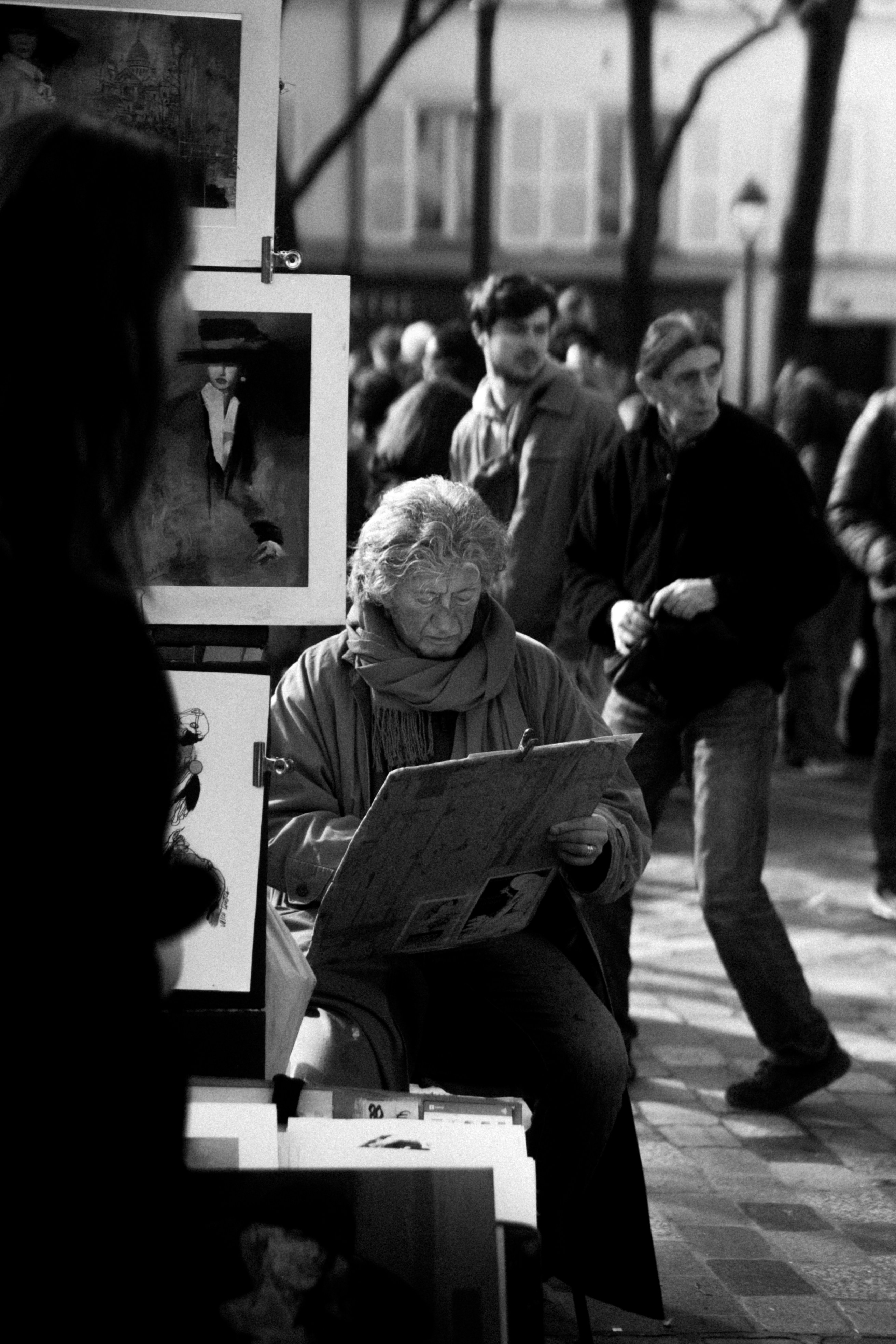 Vue de dos d'un photographe en pleine action, ajustant son appareil photo pour prendre un portrait d'une personne souriante dans un parc ensoleillé.