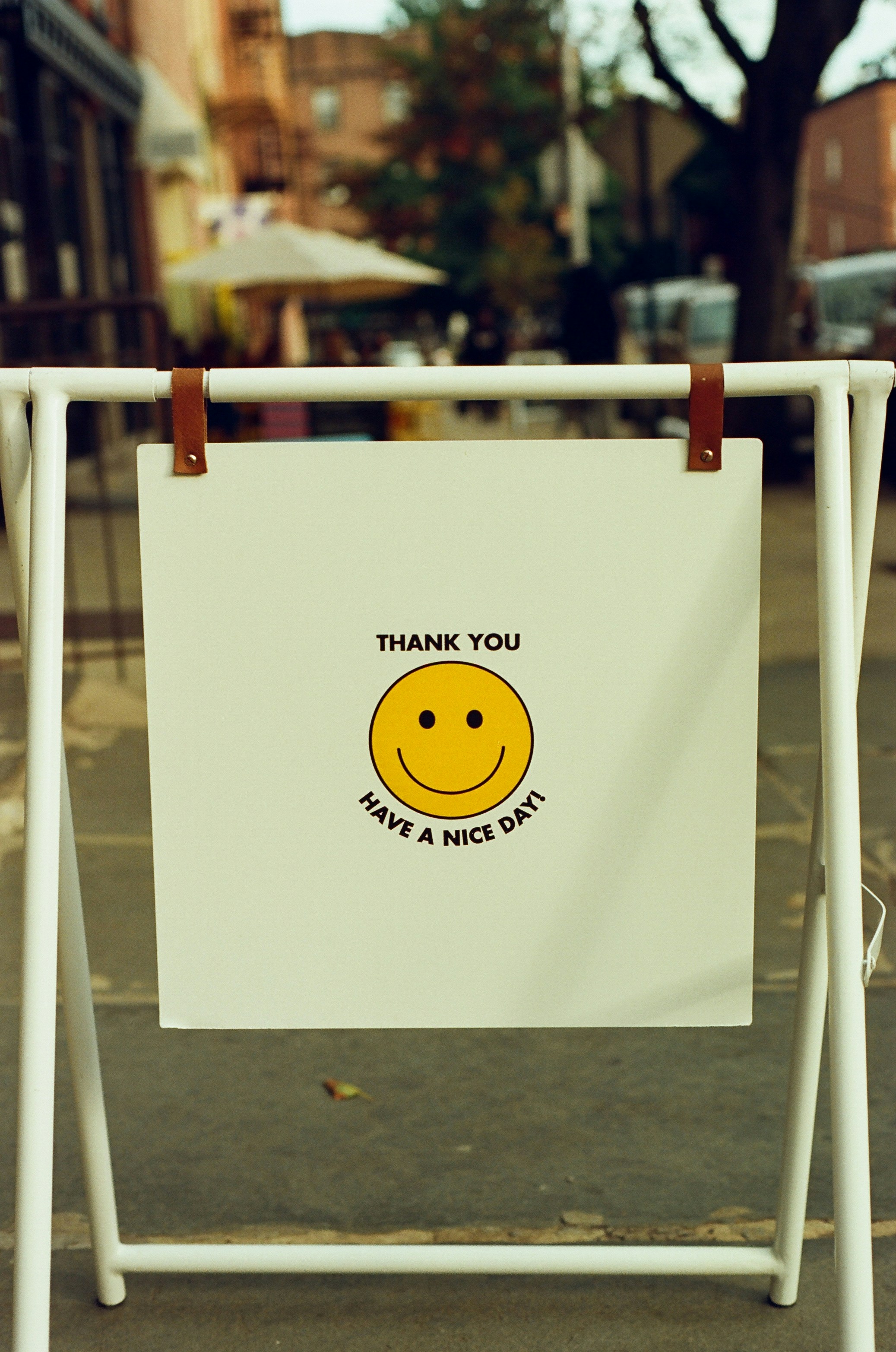 Un propriétaire de petite entreprise souriant, debout derrière un comptoir, avec une pile de flyers promotionnels fraîchement imprimés.