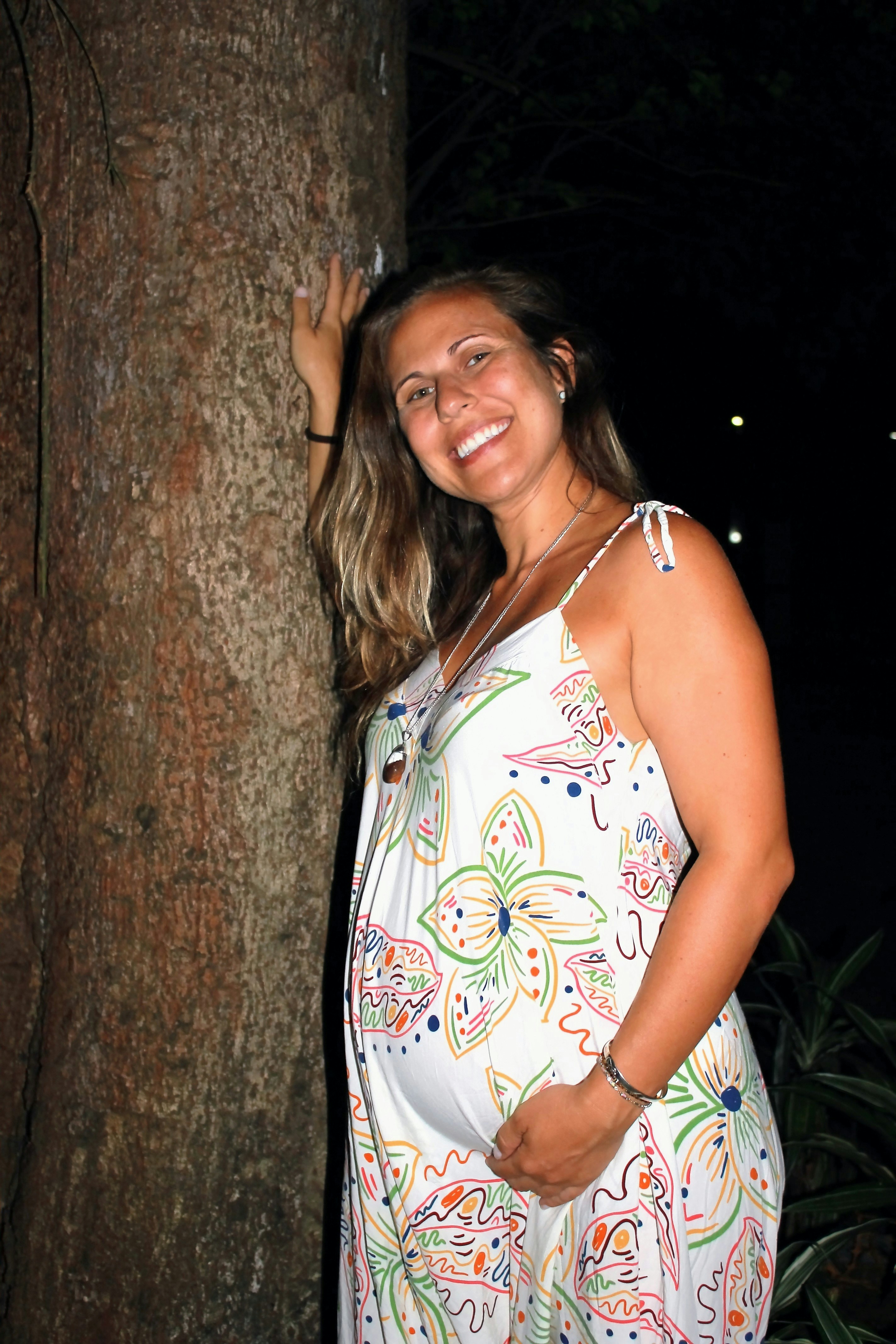 Une femme enceinte souriante et sereine, dans un cadre lumineux et naturel.