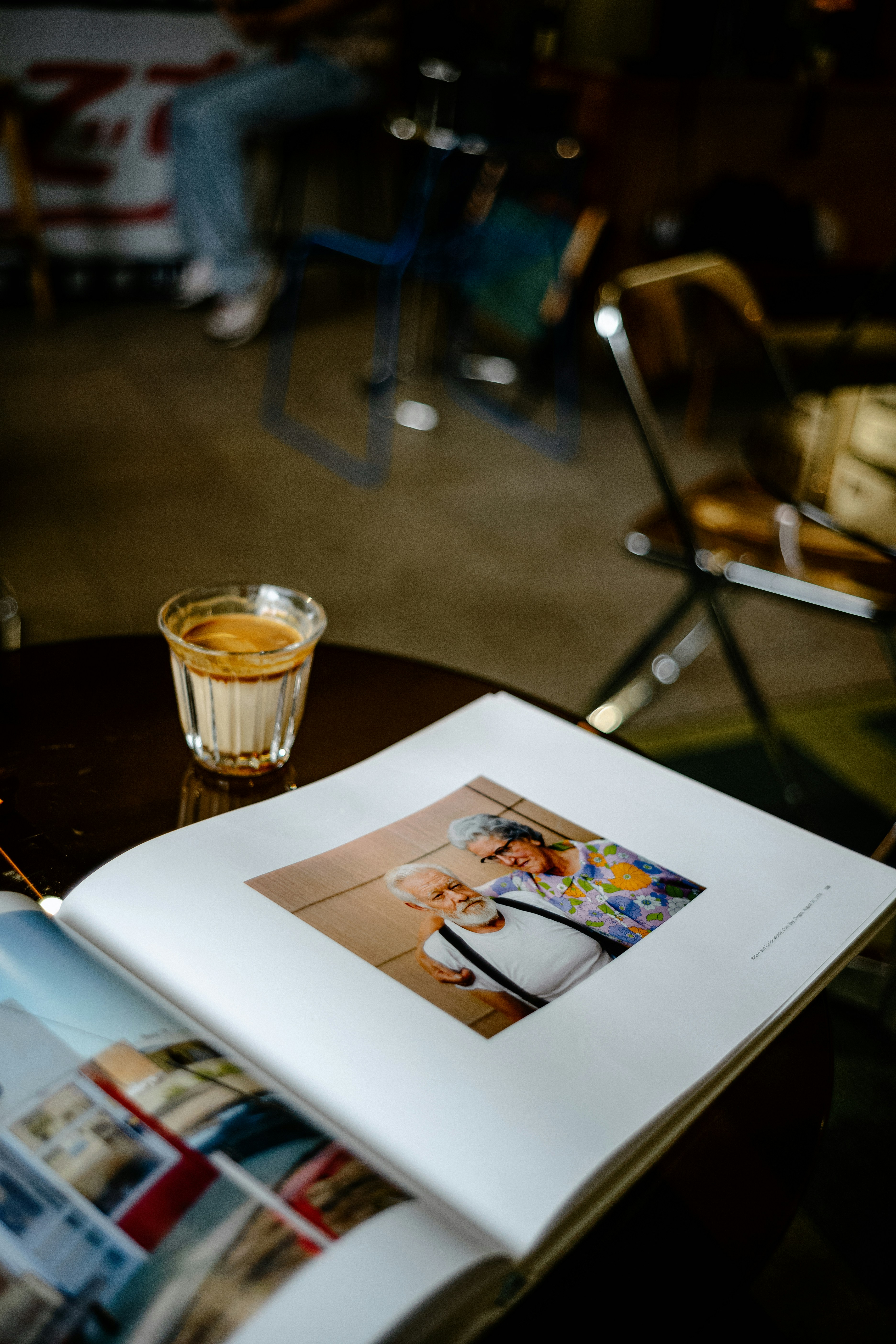 Un photographe professionnel discutant avec un couple dans un café, consultant un portfolio sur une tablette.