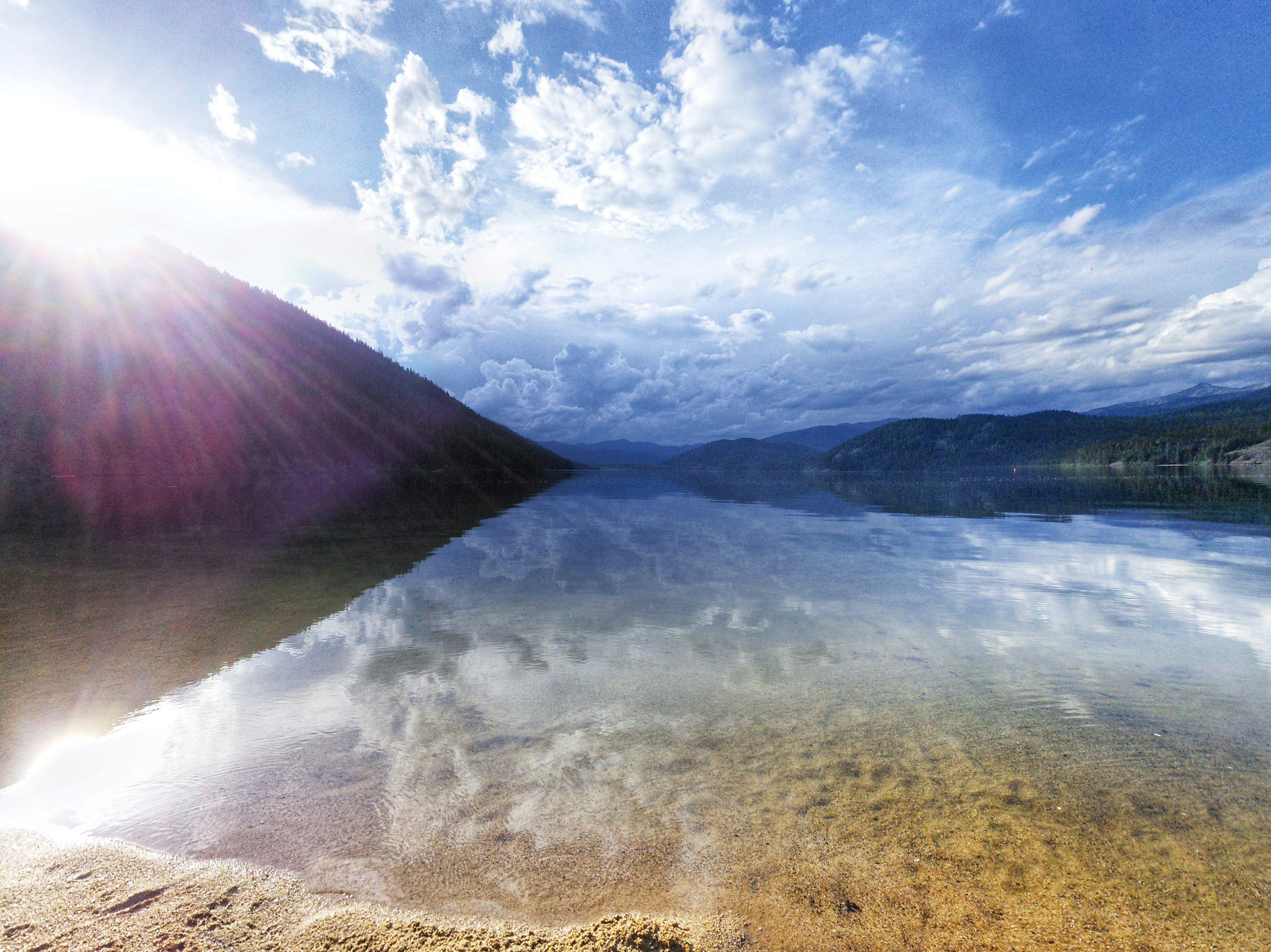 Une personne en tailleur sur un rocher, face à un lac de montagne. Une image qui inspire la clarté et l'envie de trouver de nouvelles perspectives.