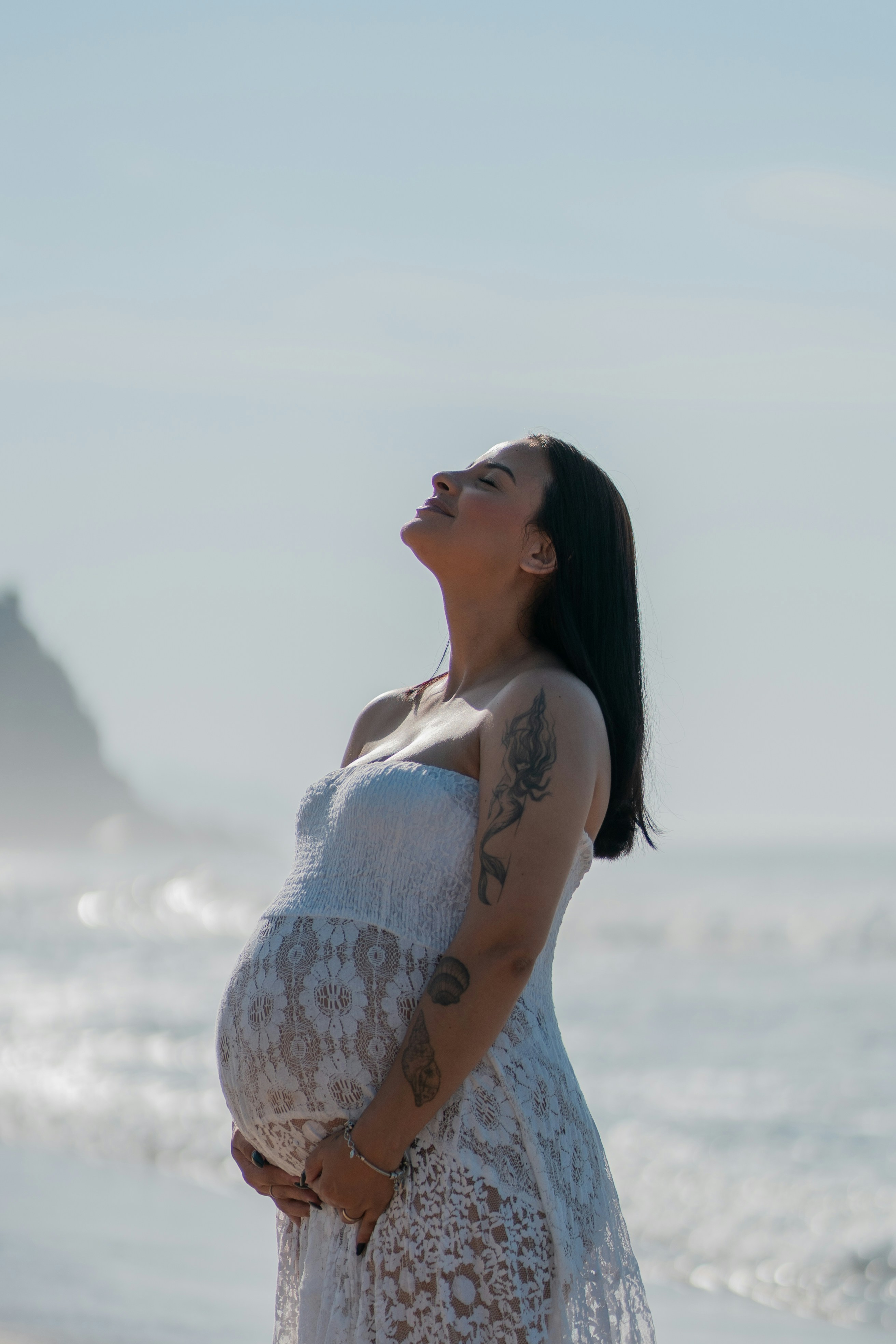 Une femme enceinte souriante assise sur un tapis de yoga dans un salon lumineux, tenant son ventre, symbole de bien-être pendant la grossesse.